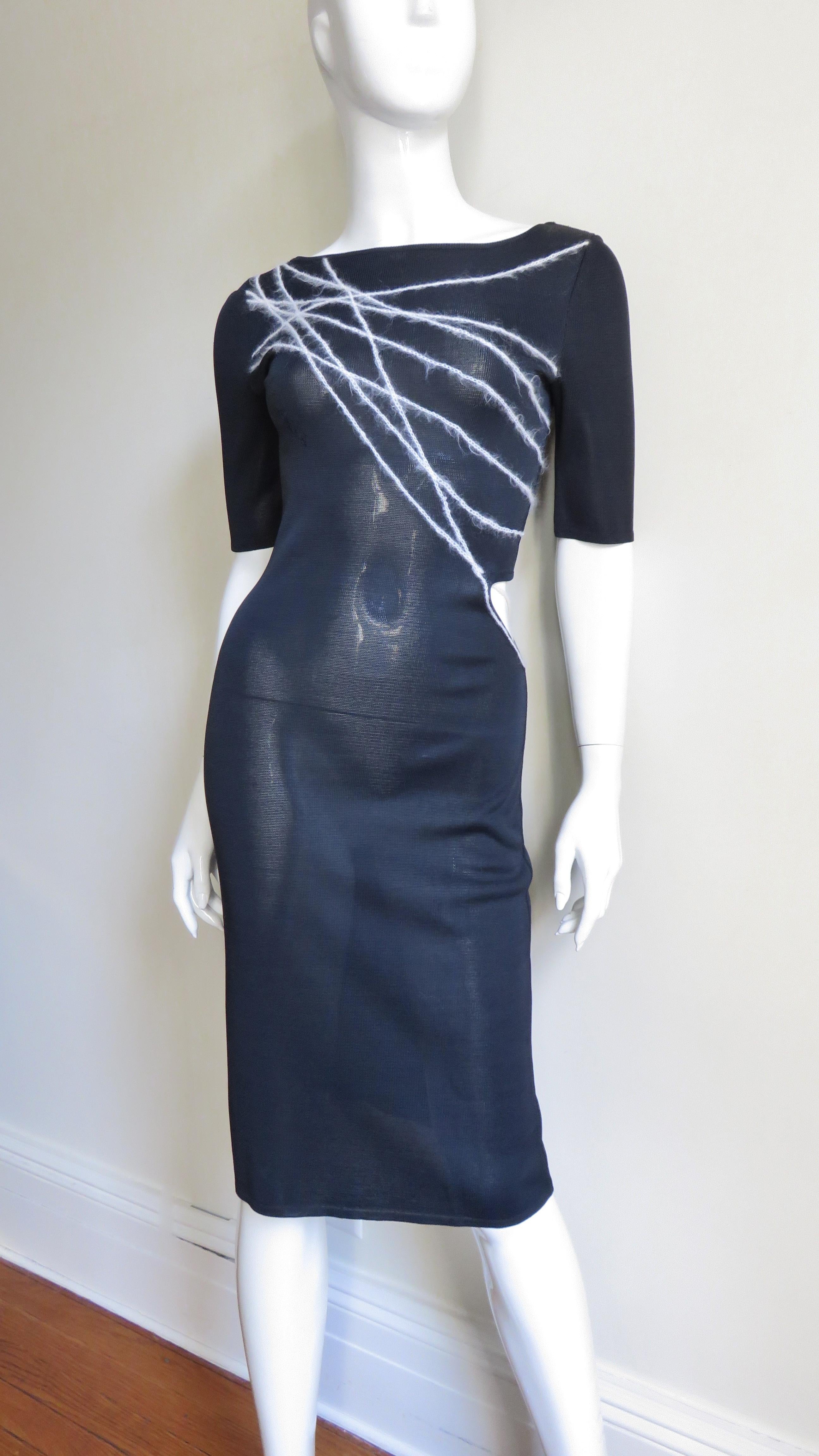 A fabulous black silk knit dress from Gianni Versace Couture.  It is semi fitted with a waist cut out at one side, elbow length sleeves and contrasting white lines of angora yarn abstractly crossing the bodice diagonally front and back.  The dress