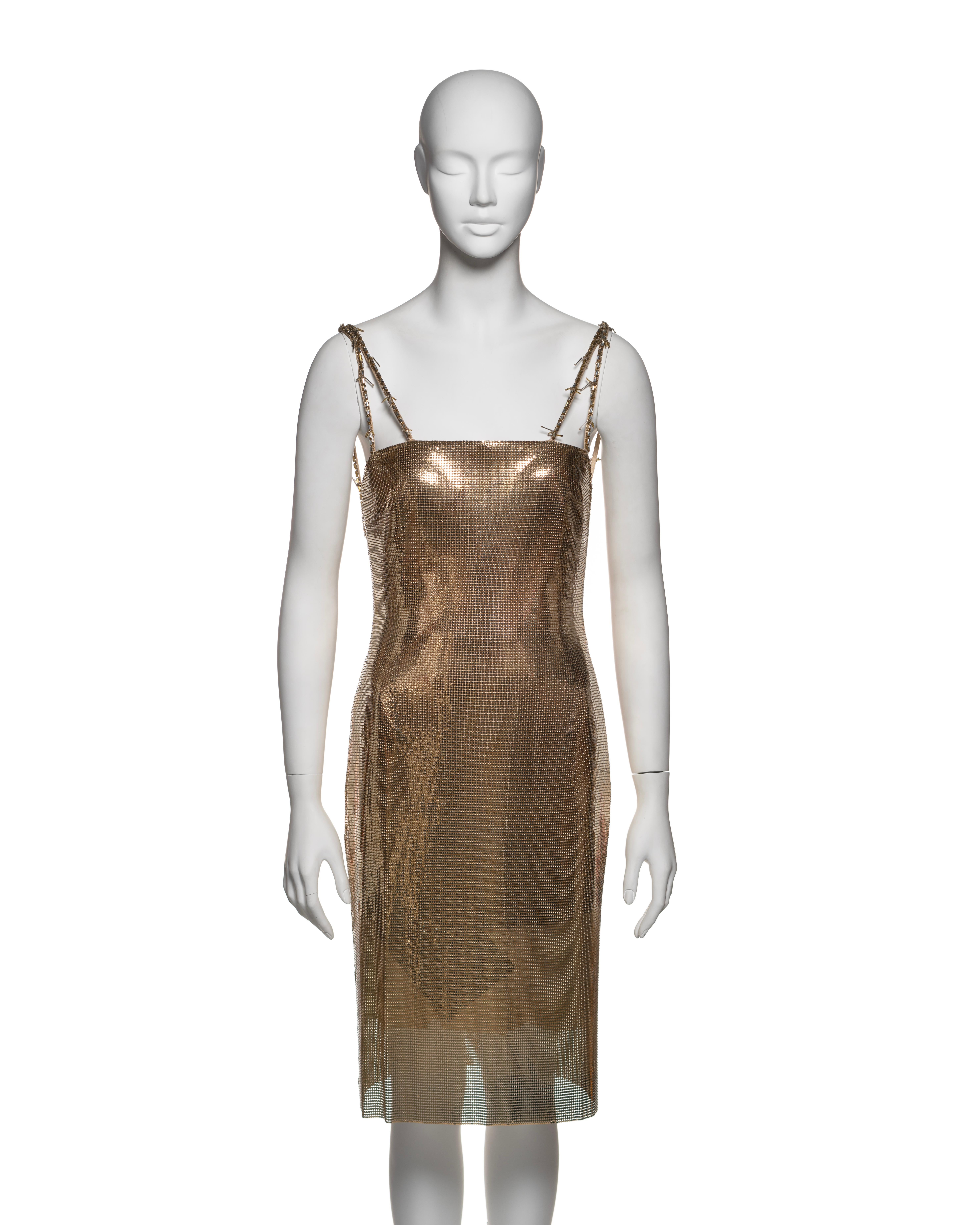 This rare Gianni Versace dress from the Fall-Winter 1998 collection is constructed from gold-tone metal mesh, showcasing a structured, fitted silhouette with a straight-cut design. The dress features double shoulder straps that resemble barbed wire,