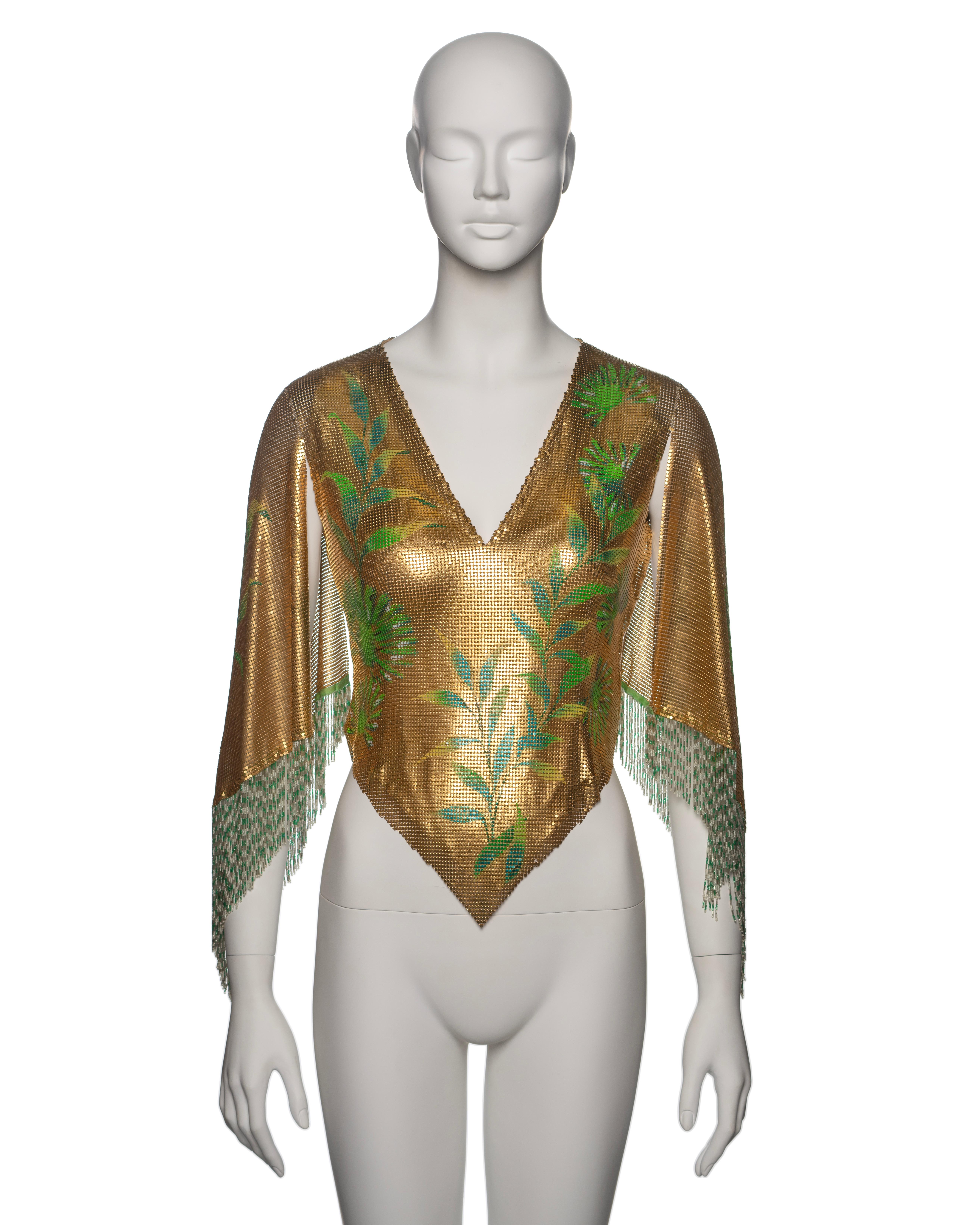 Gianni Versace Oroton, top in cotta di maglia con disegno dipinto a mano. La maglia in metallo dorato è ornata da vivaci motivi di fogliame verde sulla parte anteriore, mentre la parte posteriore mostra un'intricata immagine di Buddha multicolore.