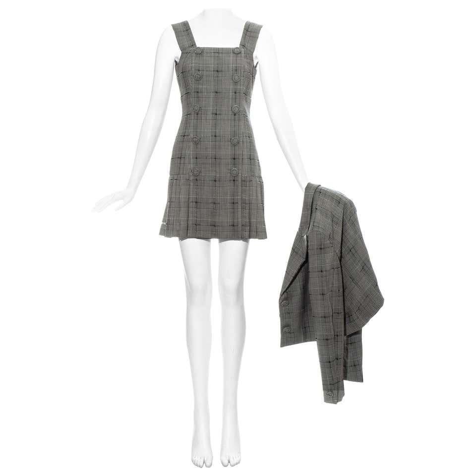 Mini robe en laine à carreaux gris Gianni Versace avec jupe plissée et 10 boutons en tissu. Veste croisée assortie, à double boutonnage, avec revers et 4 boutons en tissu.  

Printemps-été 1994