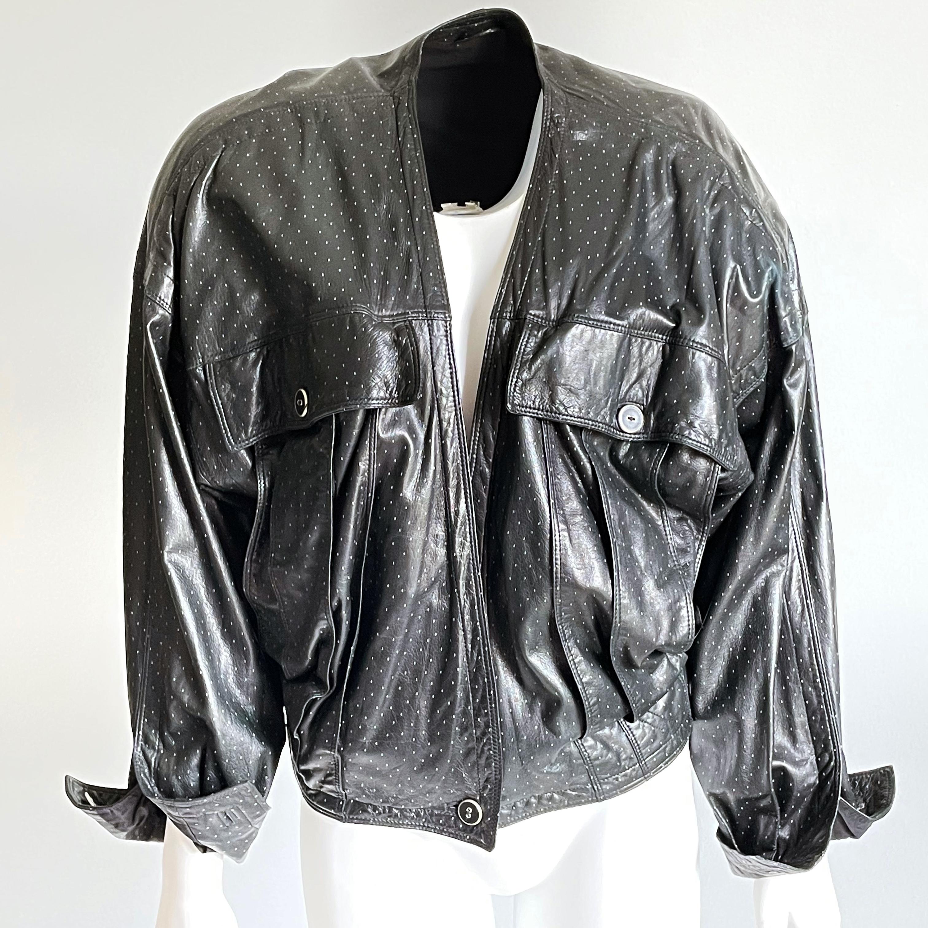 Autentico bomber in pelle Gianni Versace, usato, molto probabilmente dei primi anni '90.  Una giacca super rara! Realizzato in morbida pelle d'agnello nera con piccole macchie grigie in tutto il corpo!  Si chiude in vita con un unico bottone, è