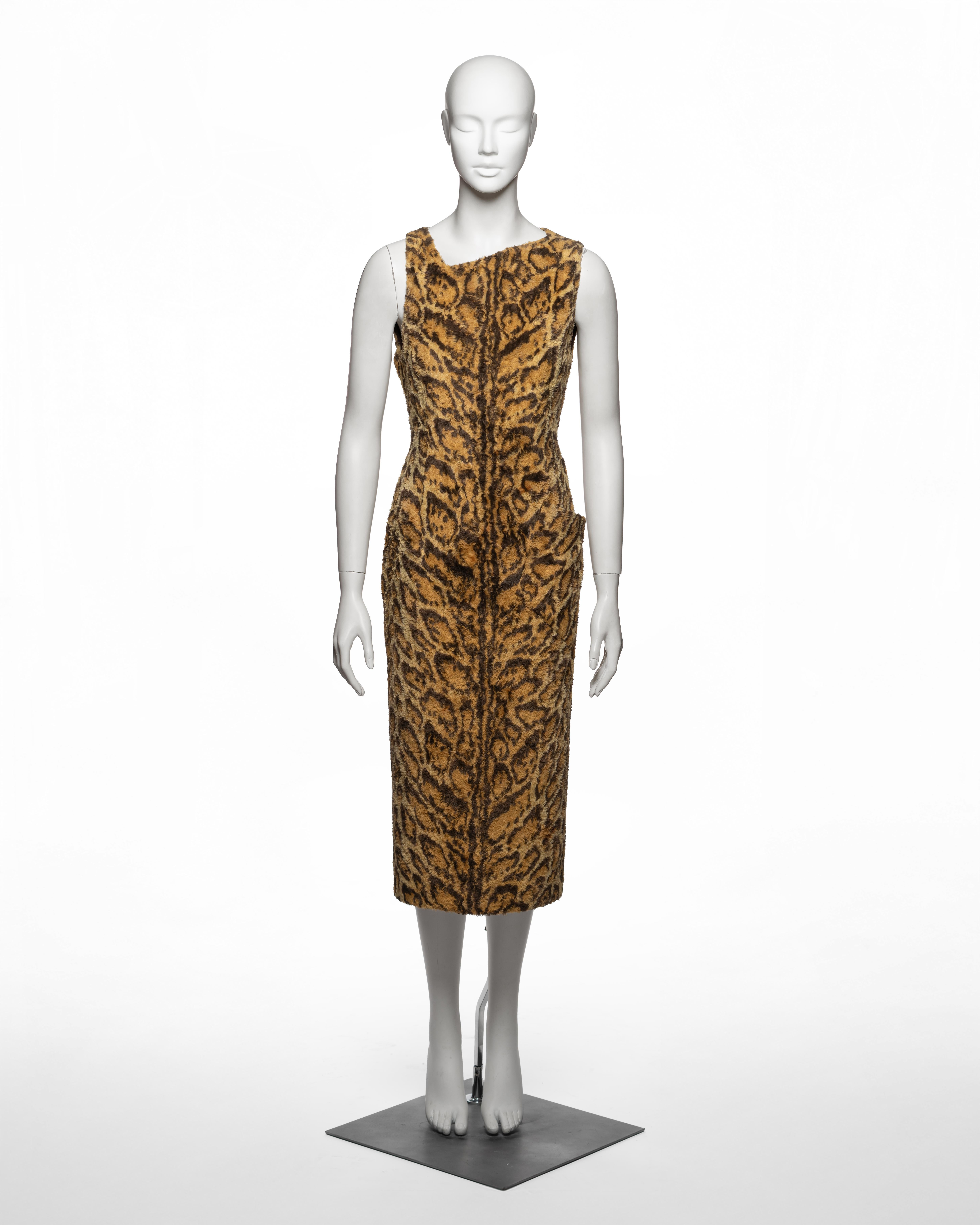 Questo abito midi senza maniche della collezione Autunno-Inverno 1996 di Gianni Versace è realizzato in una densa pelliccia sintetica a pelo alto con un motivo leopardato stilizzato nei toni dell'ocra dorato e del marrone intenso. La silhouette a
