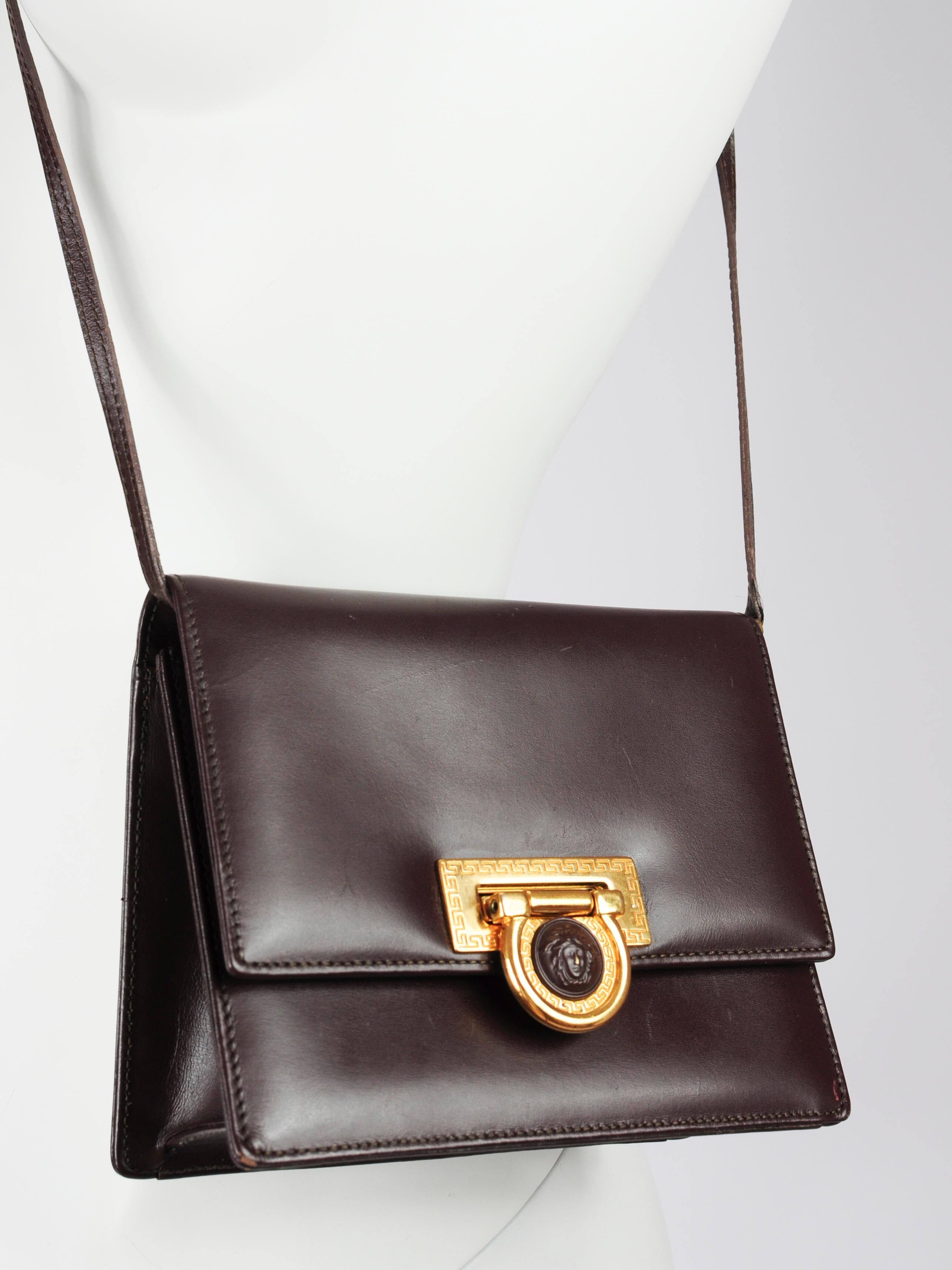 Gianni Versace brown leather crossbody bag with Versace signature medusa head closure. Along the edges of the golden hardware there are other Greek influences visible, which are something that comes back in a lot of Gianni Versace’s designs. The