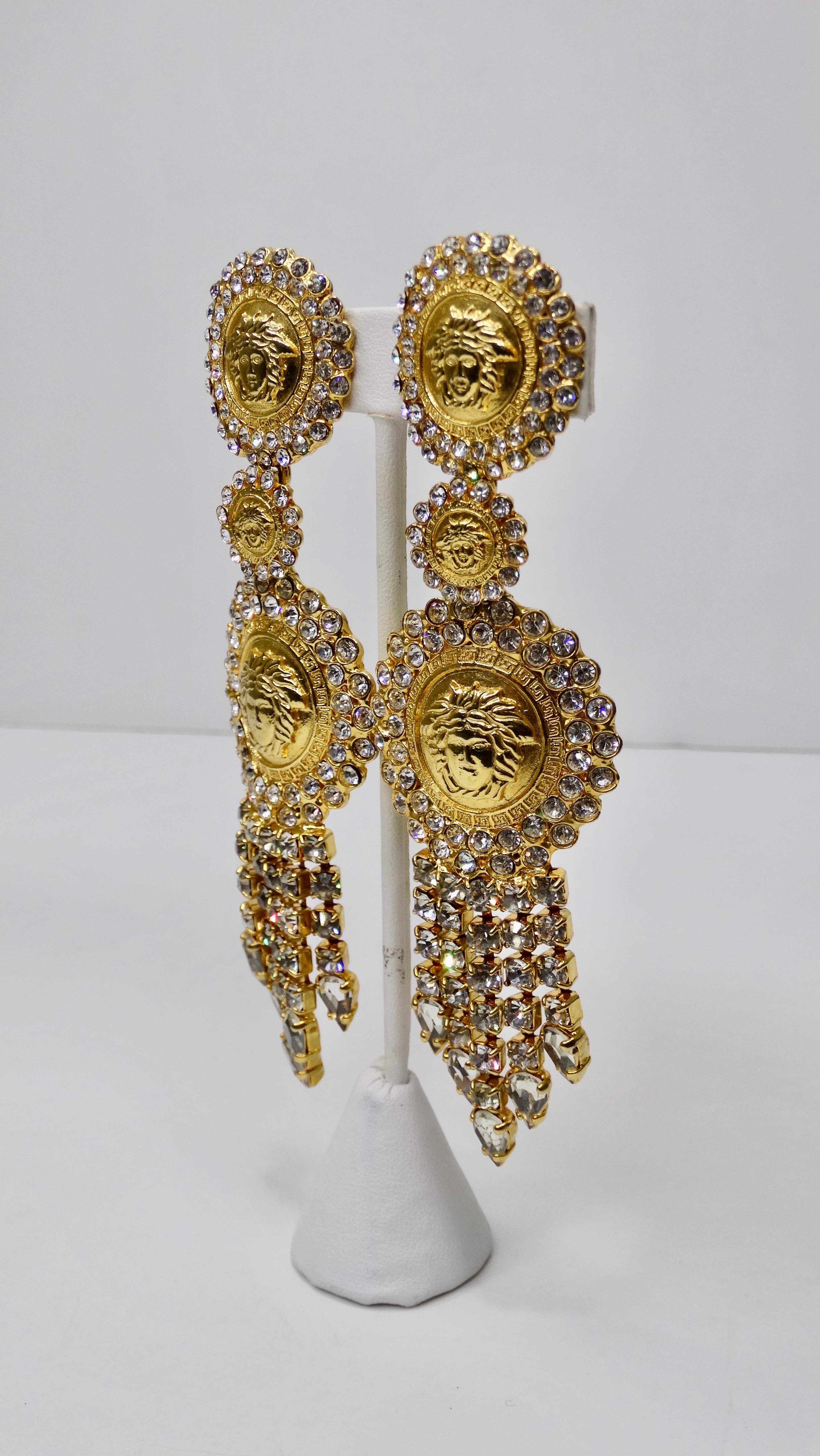 Snag yourself these hoops! Circa late 1980s/early 1990s, these gold plated Versace dangle earrings are embossed with the signature Medusa head and are embellished with rhinestones and fringe. Clip on closures. Pair with your favorite Versace silk