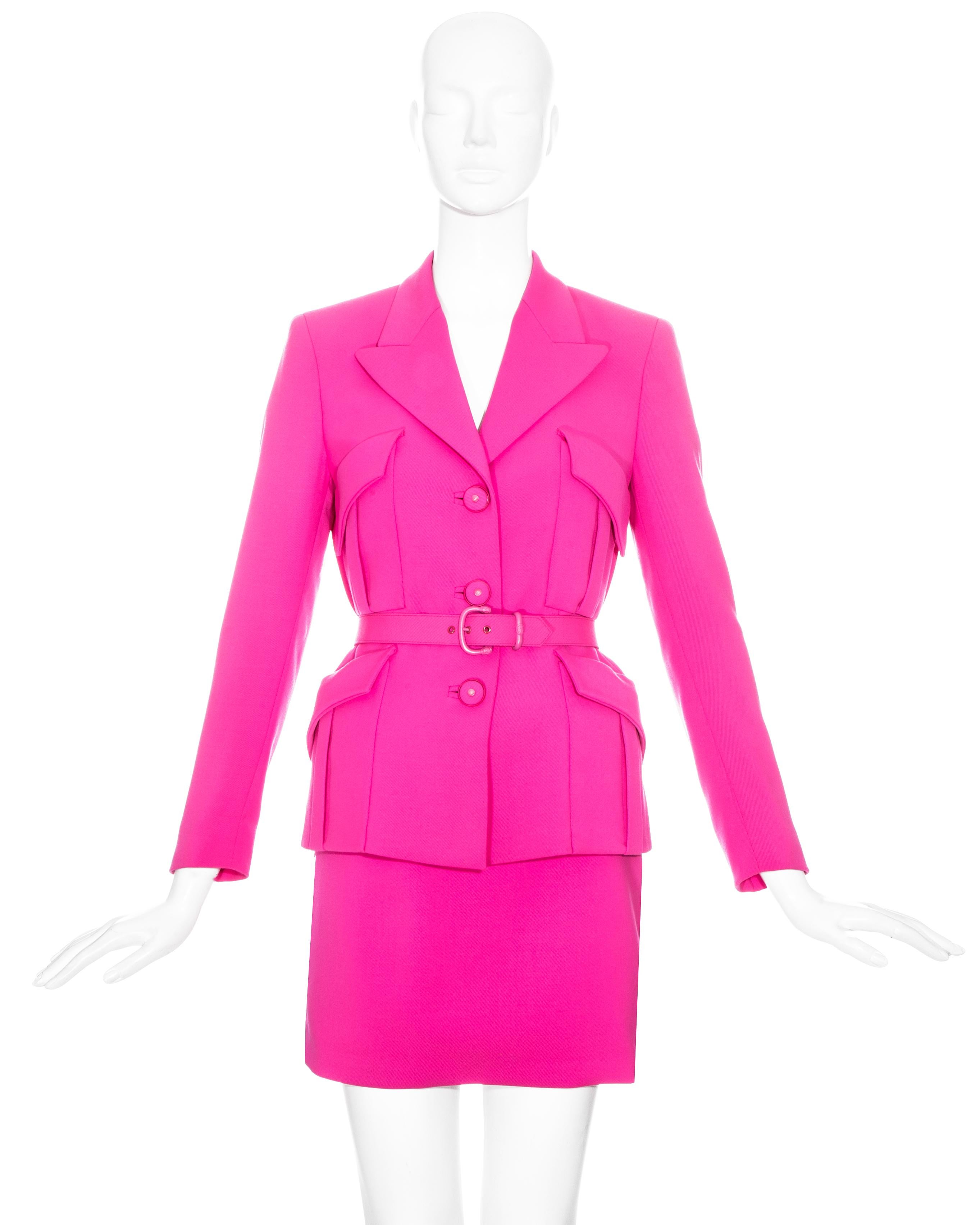 Gianni Versace neon pink wool skirt suit comprising: high waisted mini skirt, blazer jacket with four front flap pockets, large peak lapel, back vent, fabric covered Medusa buttons and matching waist belt with pink hardware. 

Fall-Winter 1996