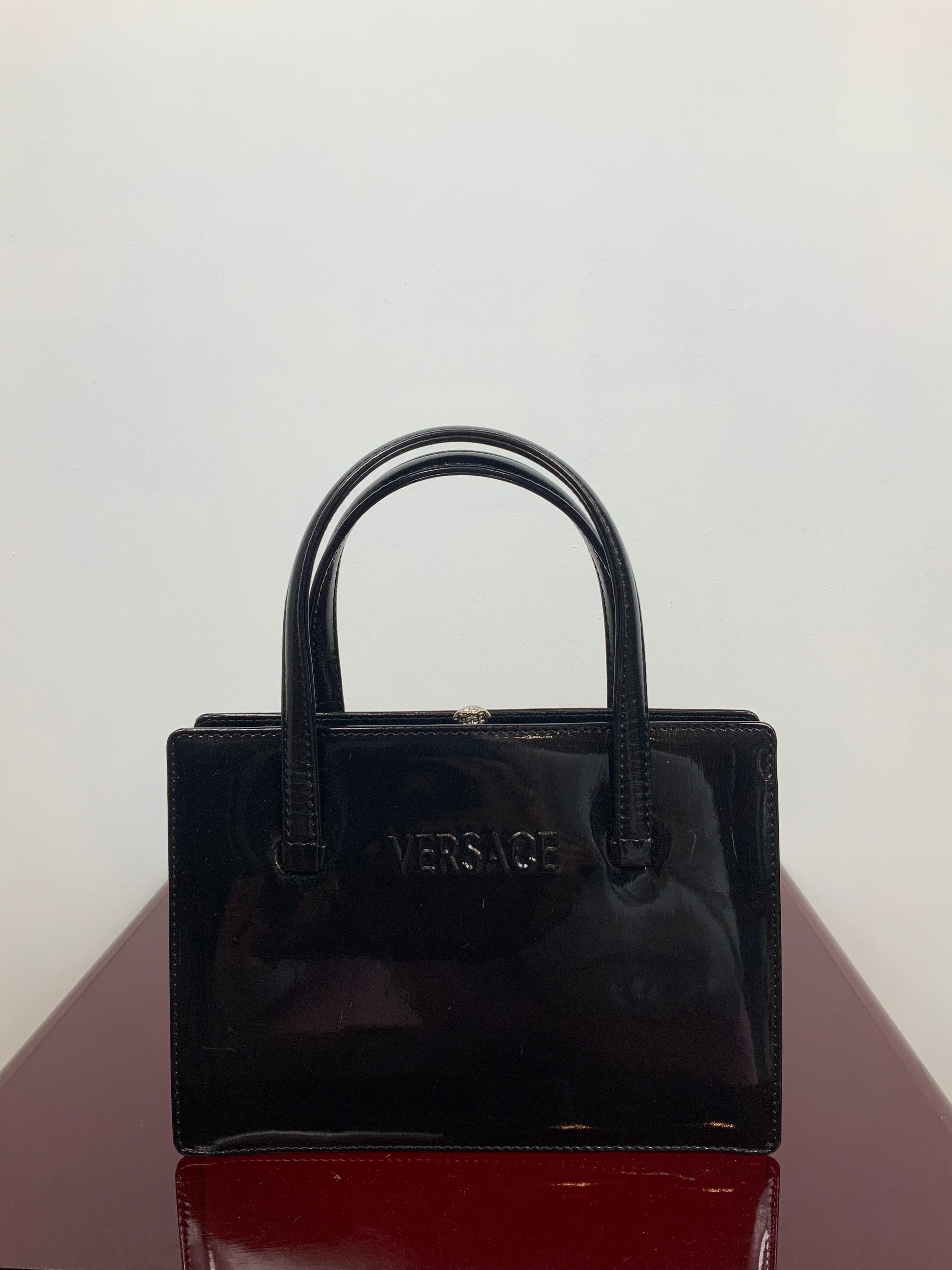 Gianni Versace bag.
Black patent leather bag.
Featuring a clip medusa-shape closure.
Measurements:
height 15 cm
width 22 cm
depth 7 cm
handle 15 cm
It comes with the original dust bag.
Conditions: Very Good - Previously owned and gently worn, with
