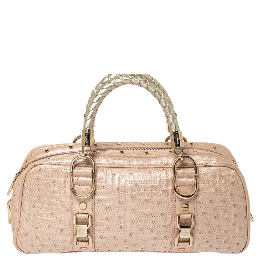 This Gianni Versace bowler bag is stylish and a perfect way to make a statement. Crafted from ostrich embossed leather in a lovely shade of peach. The exterior is quilted and carries the brand plaque. It has dual handles, zip closure and a