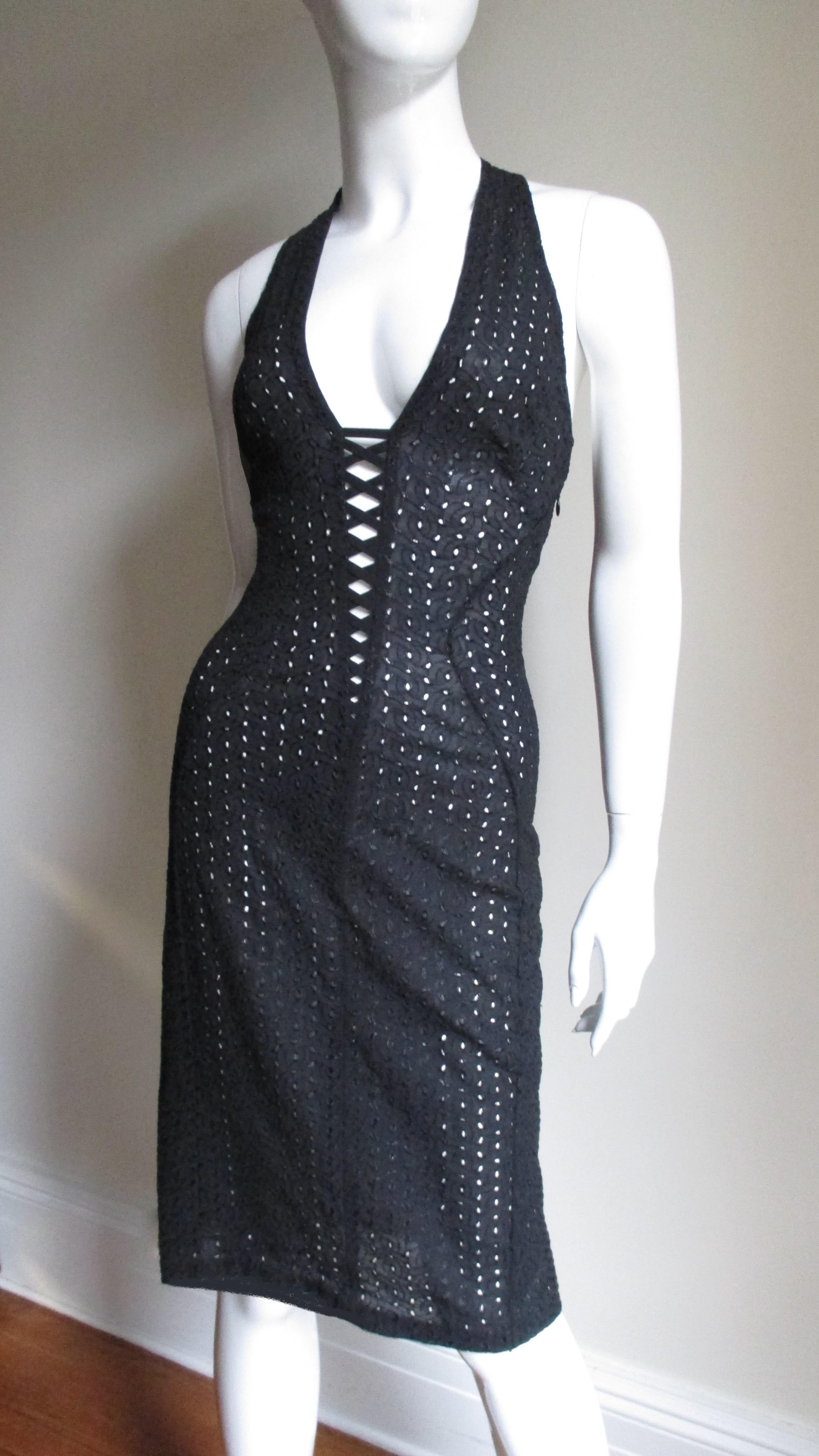 A fabulous bodycon dress in black silk eyelet by Gianni Versace Couture.  It has a plunging neckline with lacing and straps crossing at the upper back.  The dress has flattering seaming cutting in along the sides of the waist. It is unlined, has
