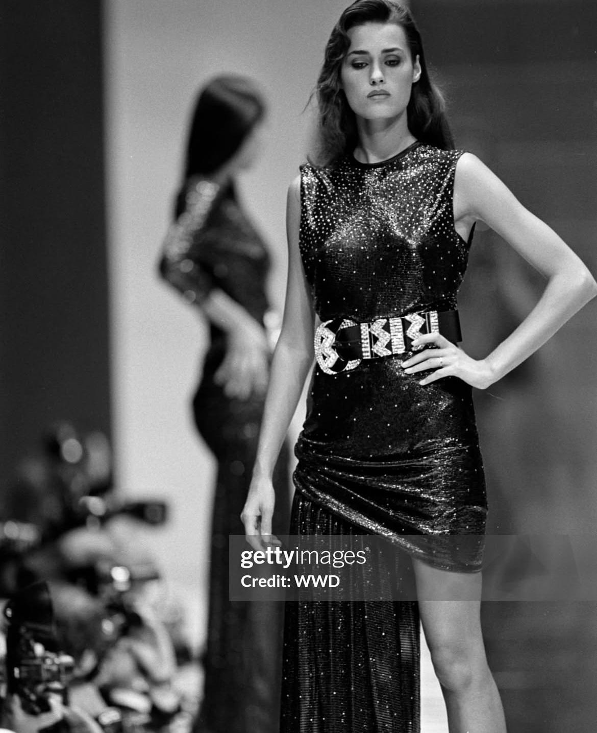 - Designed by Gianni Versace
- Sold by Skof.Archive
- Spring Summer 1988
- Orton chainmail mini dress Features a shimmering surface with intricate chainmail detail
- Sleeveless design with a figure-hugging silhouette
- Asymmetric draping at the