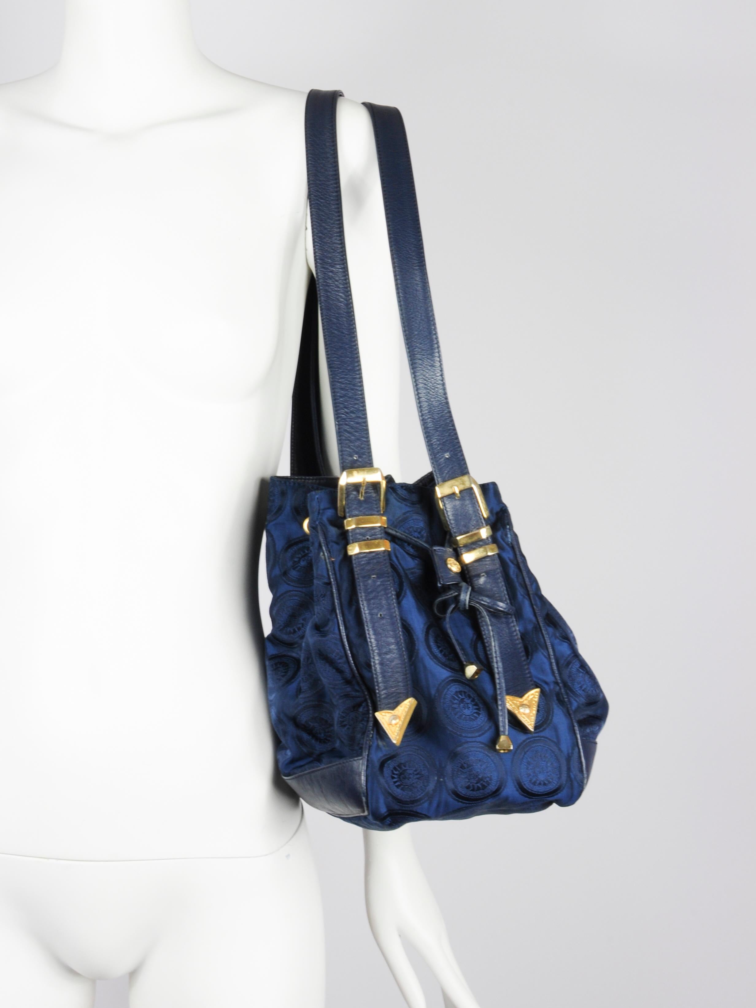 Gianni Versace shoulder bucket bag in navy blue with sun print and western and medusa details from the 1990s. The all-over signature Versace sun print in navy blue is beautiful and plays with the light. On the front the Gianni Versace name is