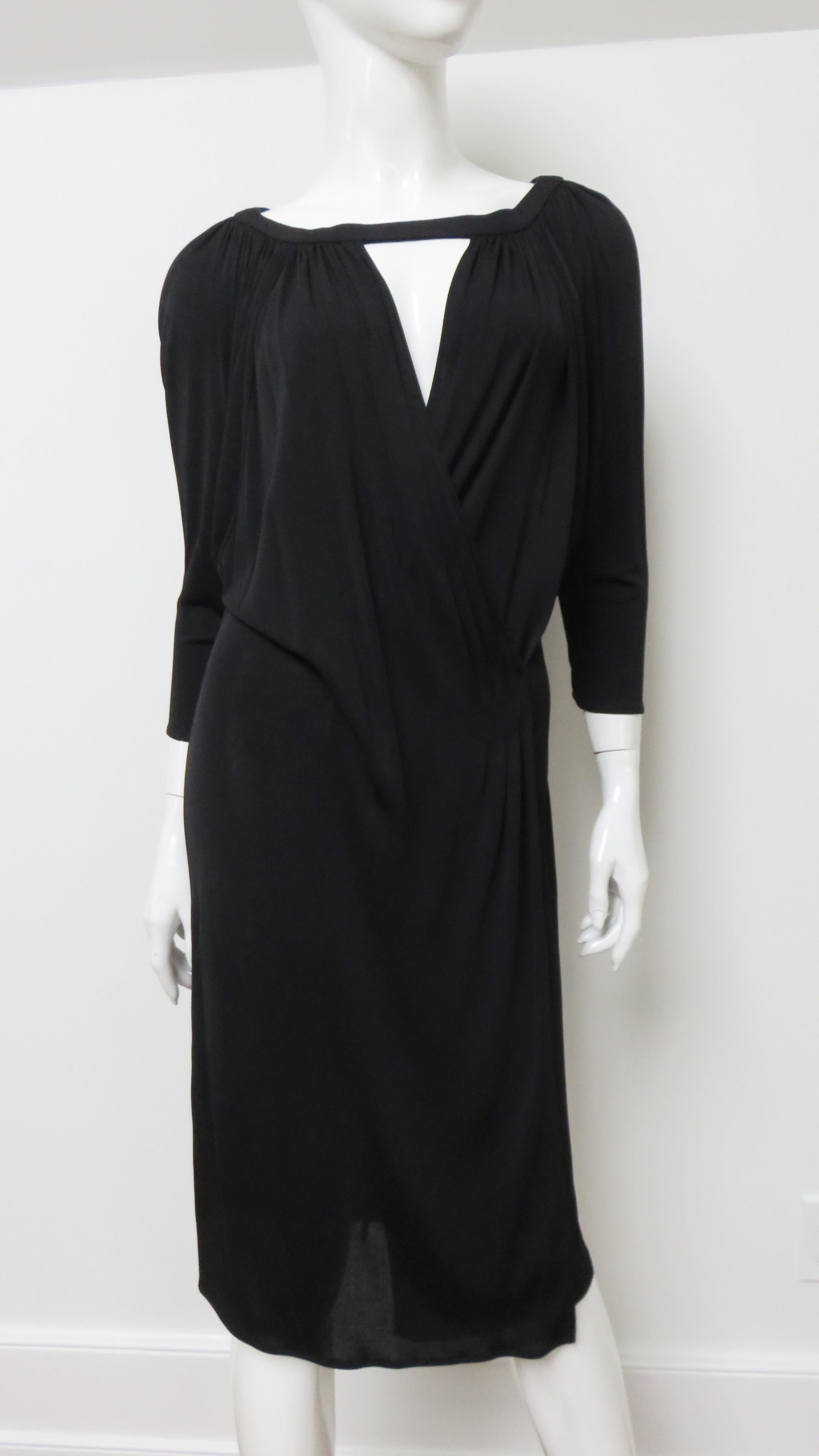 A beautiful black fine knit silk dress from Gianni Versace.  It has a crossing front with a V cut out at the neck, 3/4 length dolman sleeves and draping to hip level.  The skirt portion wraps and is straight.  No closures, it slips on over the