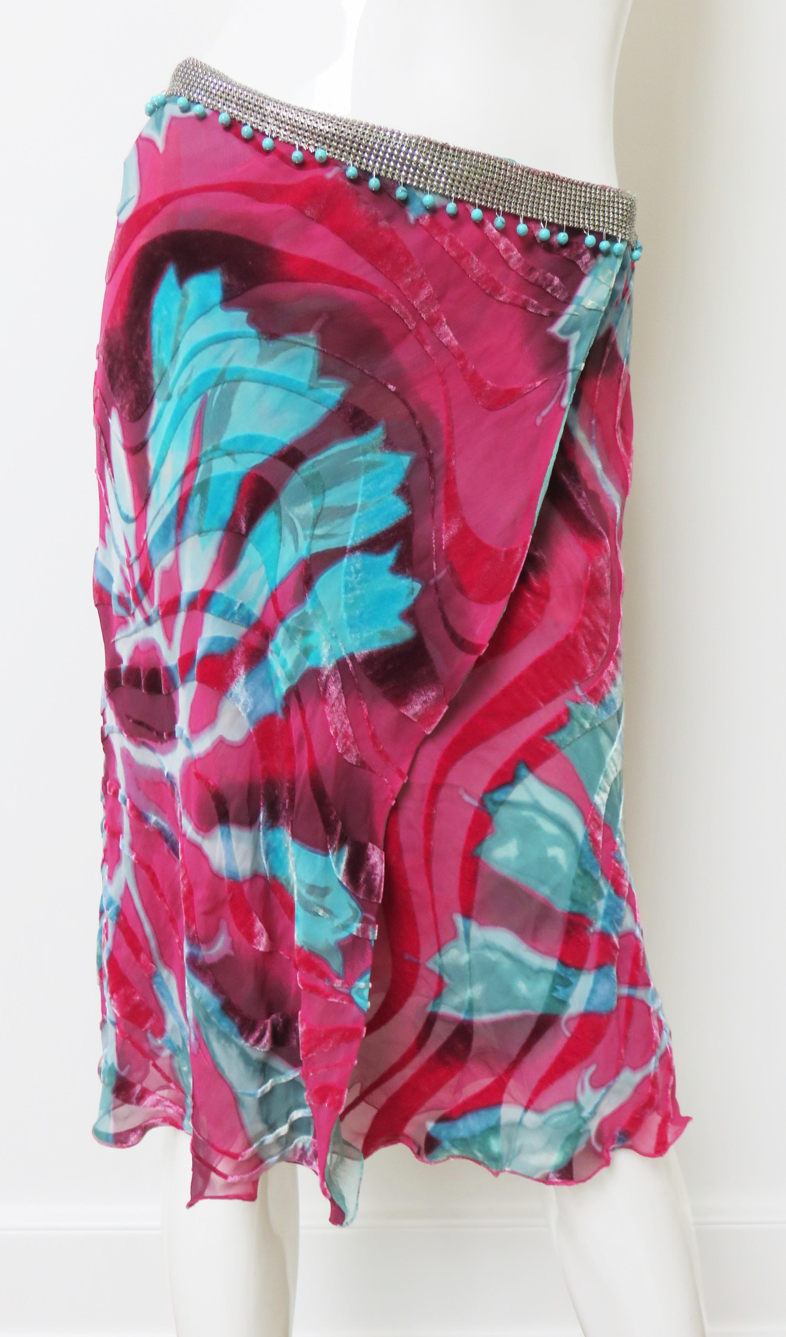 A gorgeous cut velvet wrap skirt by Gianni Versace in a beautiful bold pink and turquoise flower pattern.   It has an metal mesh or chain mail band around the waist with dangling turquoise beads.  It wraps closing at the waist with silk covered