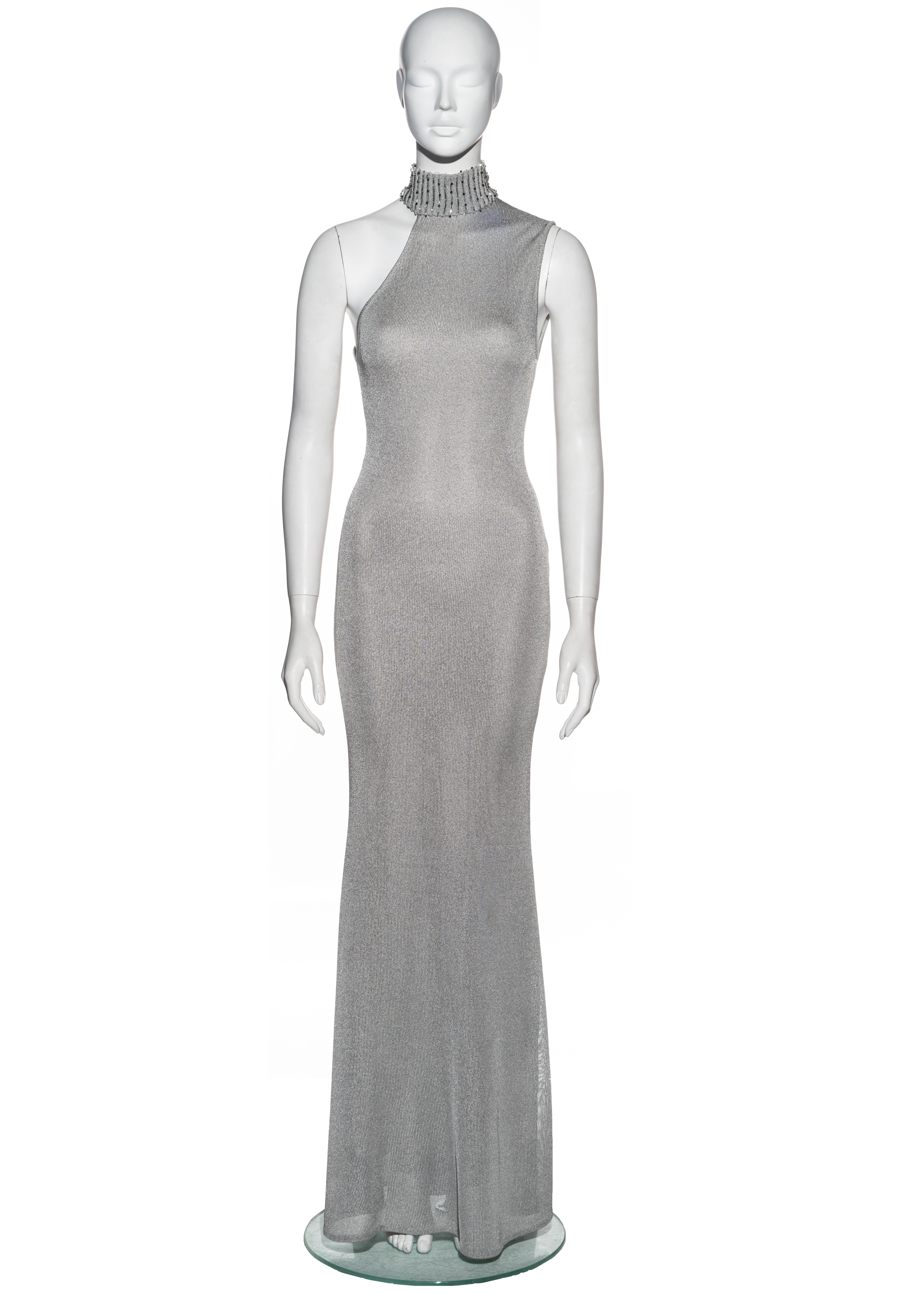 ▪ Gianni Versace silver knitted rayon evening dress
▪ Sold by One of a Kind Archive
▪ Fall-Winter 1996
▪ Ribbed turtleneck with beaded vertical striped design
▪ Asymmetric neckline
▪ Floor-length skirt 
▪ Fully lined 
▪ 71% Rayon, 15% Acetate, 14%