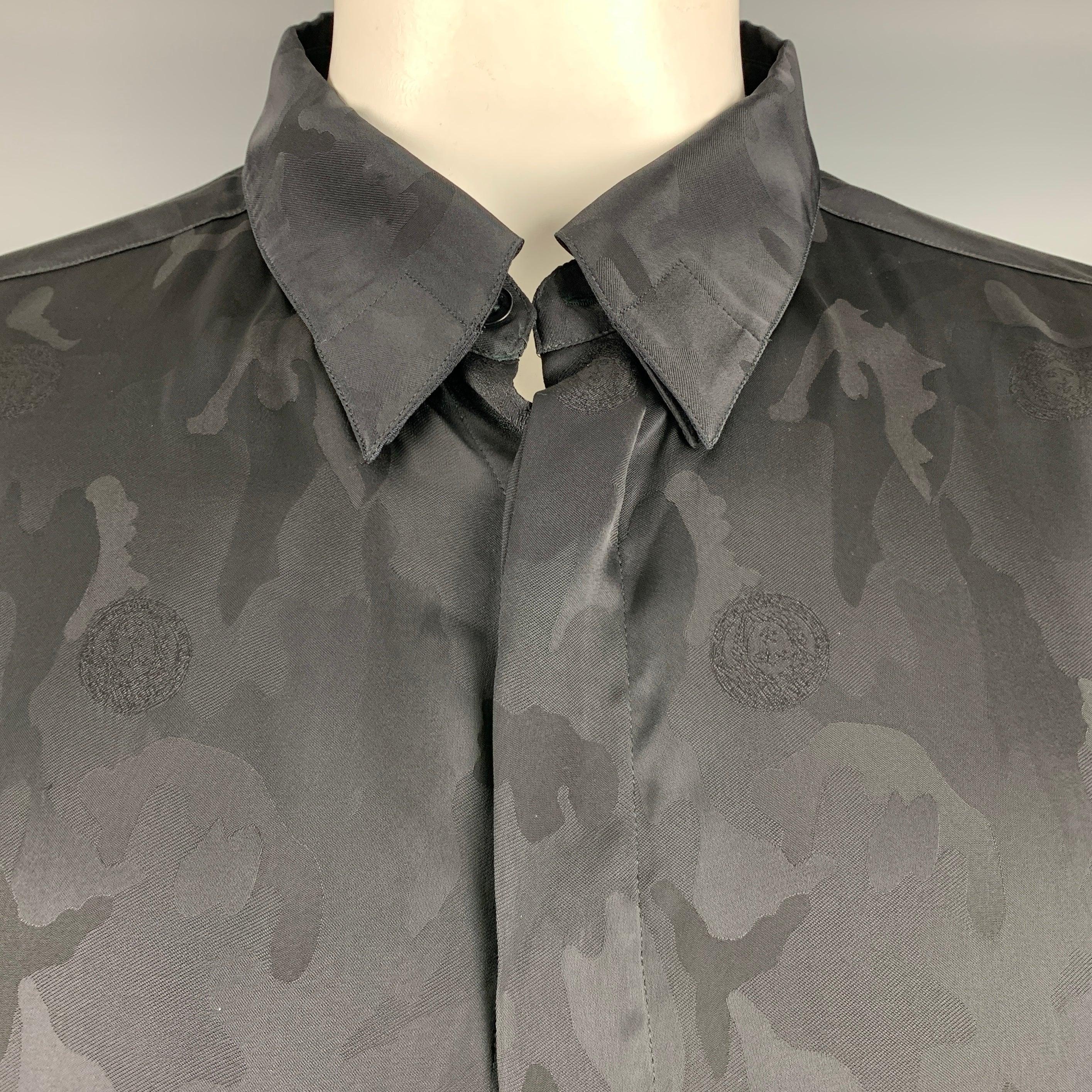 Vintage GIANNI VERSACE long sleeve shirt
in a black silk fabric featuring a camouflage pattern with signature Medusa head logo, hidden button down collar, and hidden button closure. Made in Italy.Excellent Pre-Owned Condition. 

Marked:   58