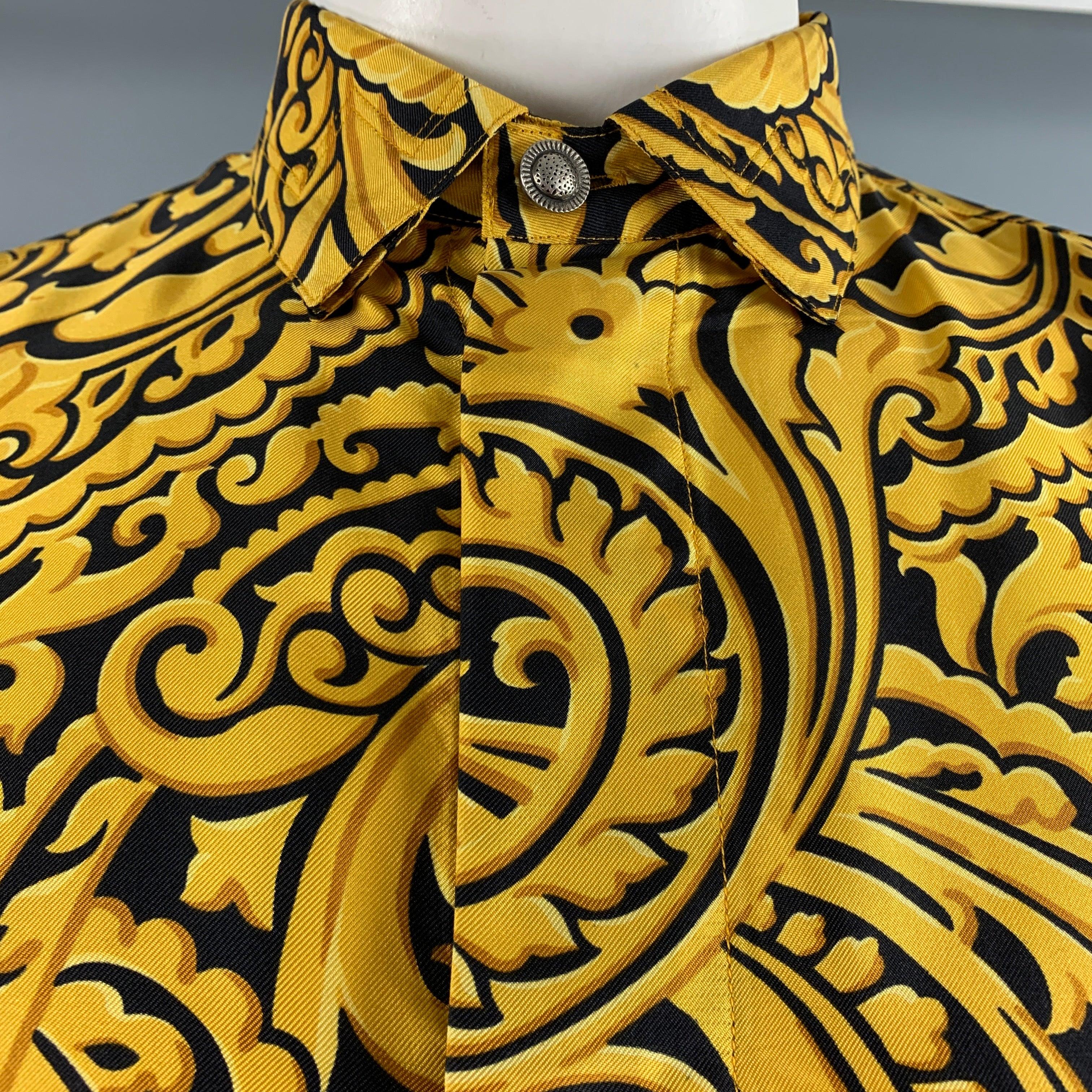 VERSUS by GIANNI VERSACE VINTAGE long sleeve shirt comes in a black and gold printed silk woven material featuring a drop shoulder, straight collar, and a hidden packet with button up closure. Made in Italy.Excellent Pre-Owned Condition. 

Marked:  