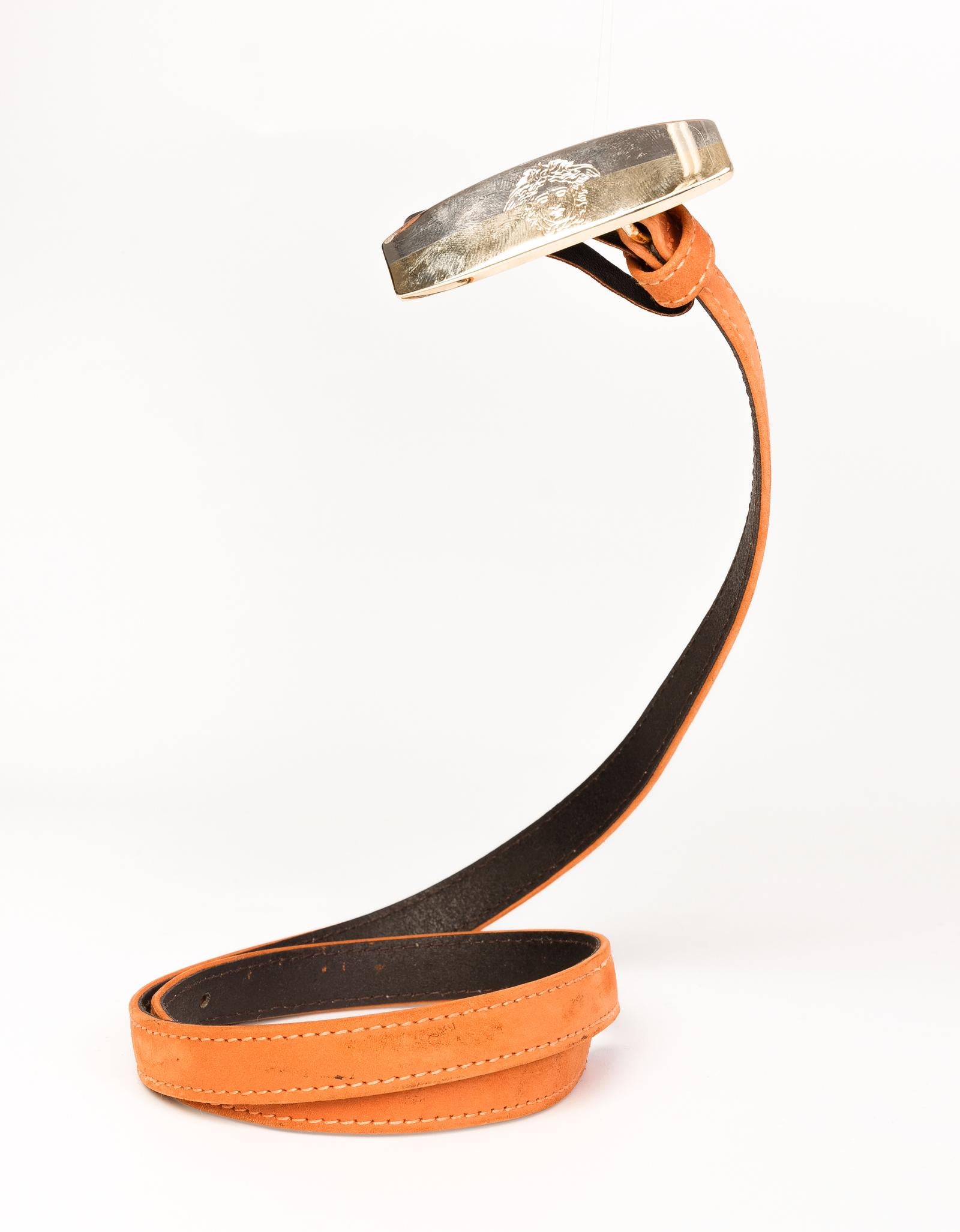 Versace thin orange leather belt with a plain gold and silver tone front hardware with the iconic Medusa head. 

COLOR: Orange
MATERIAL: Leather
ITEM CODE: D 5033 NB1
MEASURES: L 30” x W .5”
SIZE: 65/26
CONDITION: Very good  -  small signs of wear