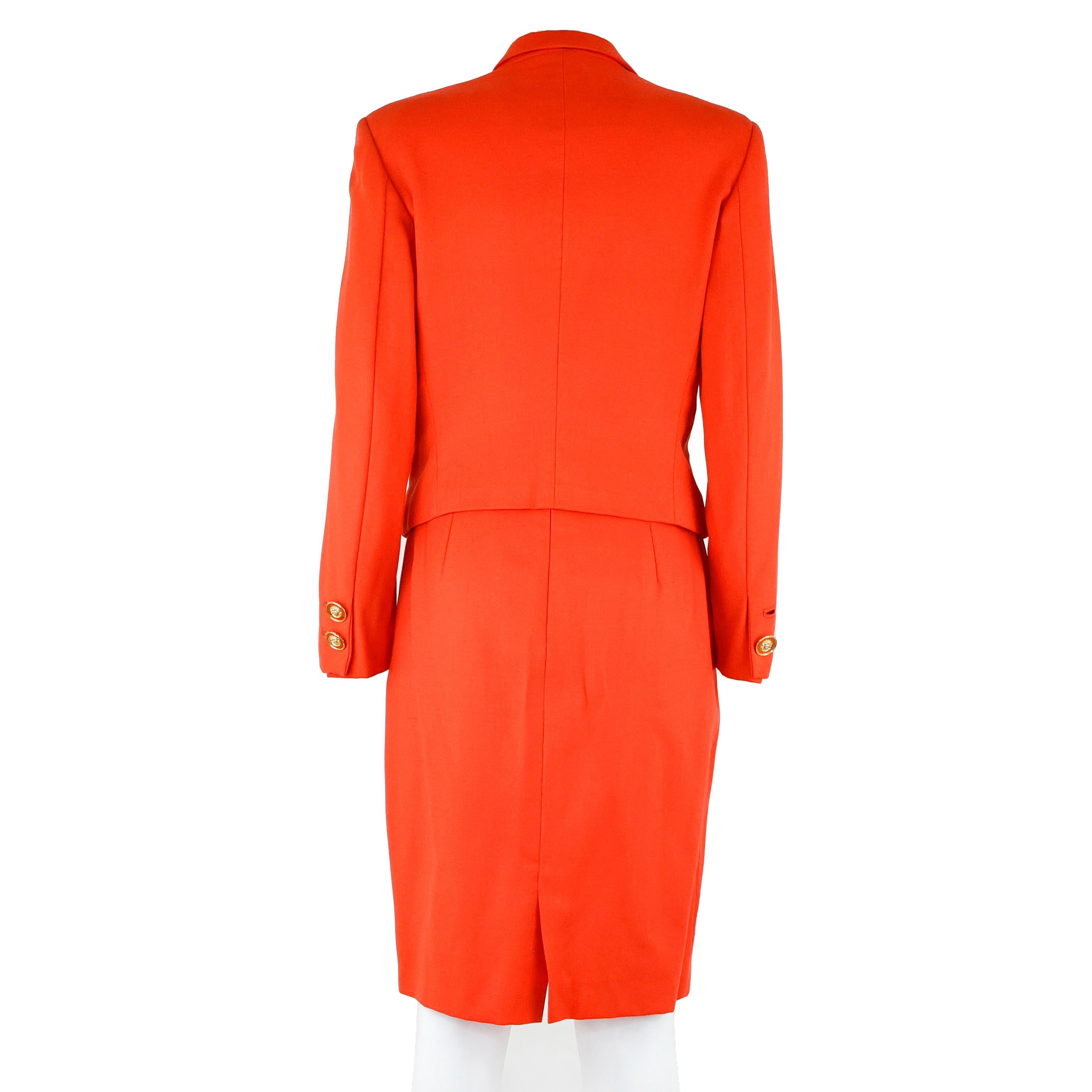 Abito / Tailleur (giacca e gonna) di Gianni Versace in lana color arancio, con bottoni dorati a forma di medusa.

Condizioni:
Davvero buono, piccoli segni del tempo, da notare: un bottone mancante sulla chiusura del polsino.