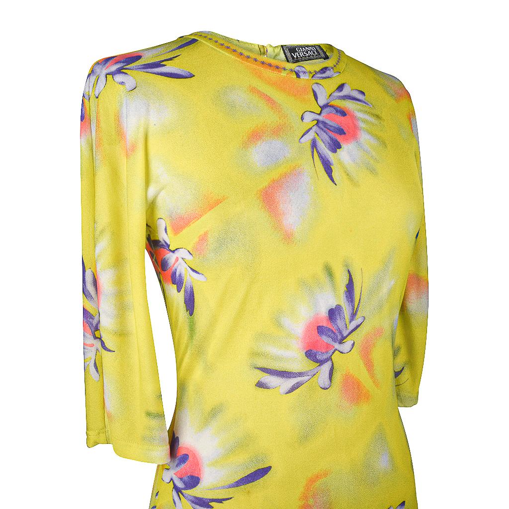 Guaranteed authentic vintage Gianni Versace top features a semi sheer top with a floral pattern.  
3/4 length sleeve top with a lime background and flowers in orange, pink and purple.
Pull on top with round neckline.
Rear keyhole with embossed