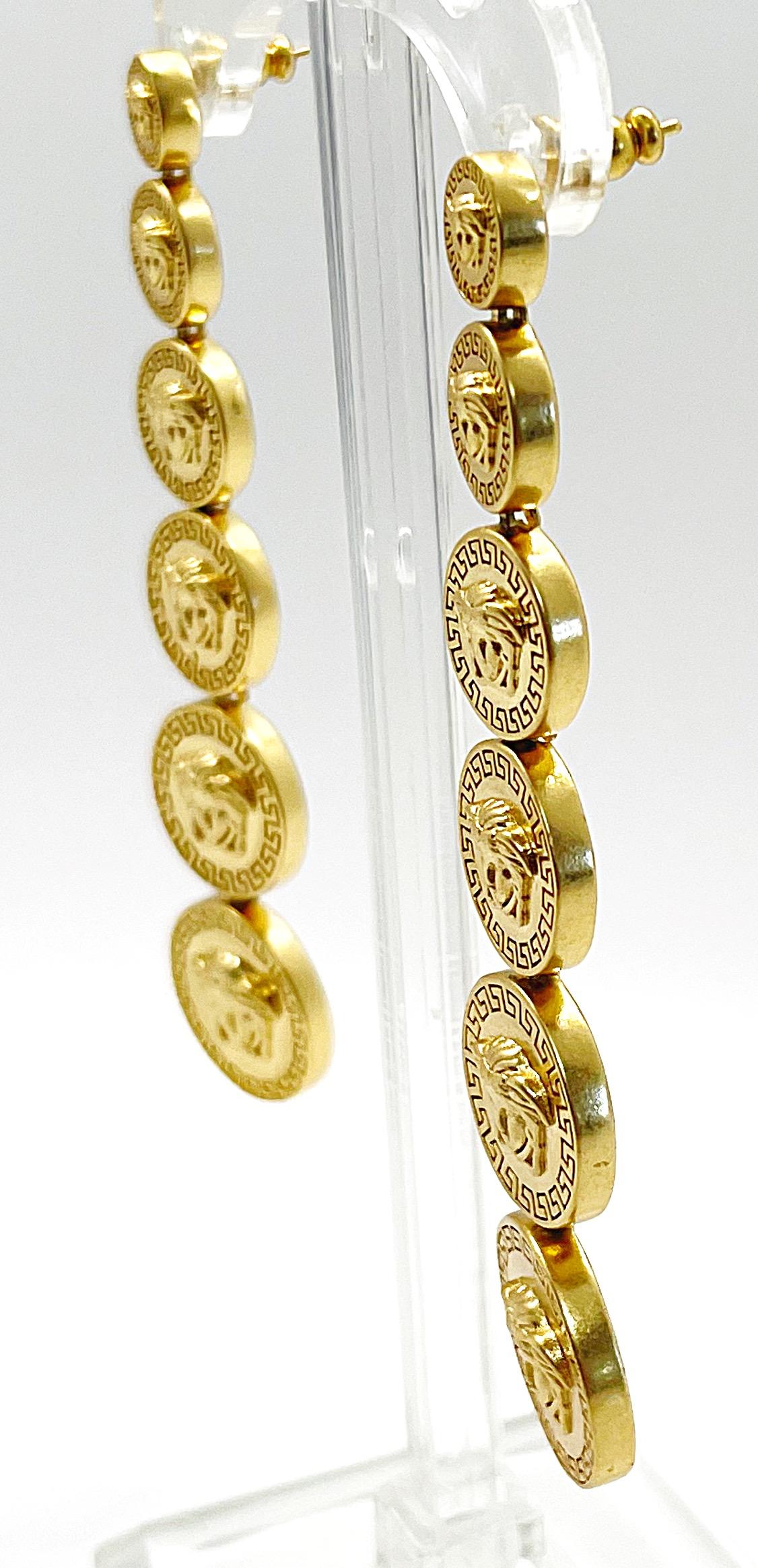 Iconic never worn GIANNI VERSACE gold Medusa head embossed dangle pierced back earrings. Each earring features 6 discs. Pierced back. Can easily be dressed up or down.
In great unworn condition
Made in Italy
Measures 3.5 inches long  