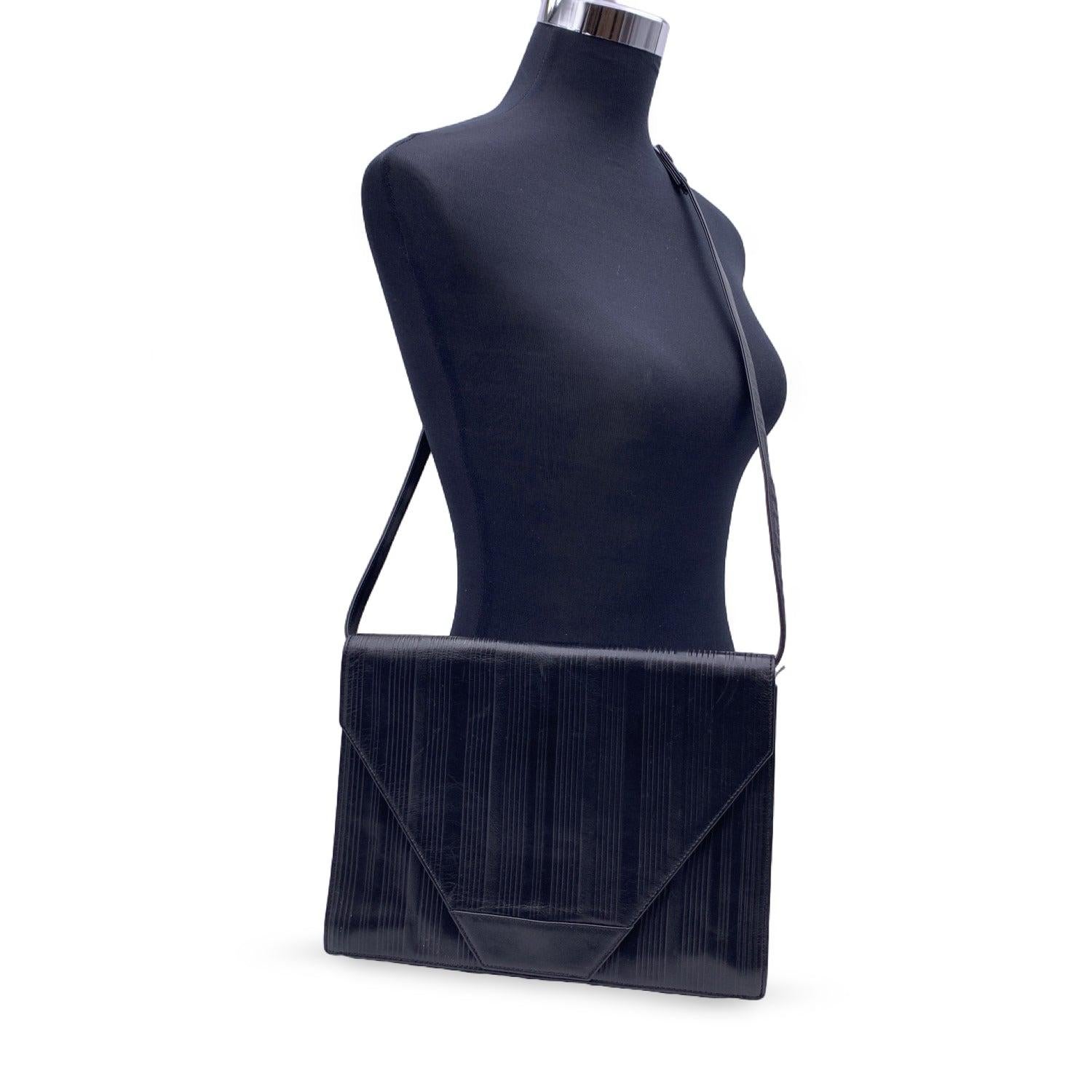 Gianni Versace Vintage Umhängetasche oder Clutch aus schwarzem, geripptem Leder. Sie hat eine Klappe mit Magnetknopfverschluss auf der Vorderseite. Abnehmbarer Schultergurt. Schwarzes Stofffutter. 1 Seitentasche mit Reißverschluss innen. GIANNI
