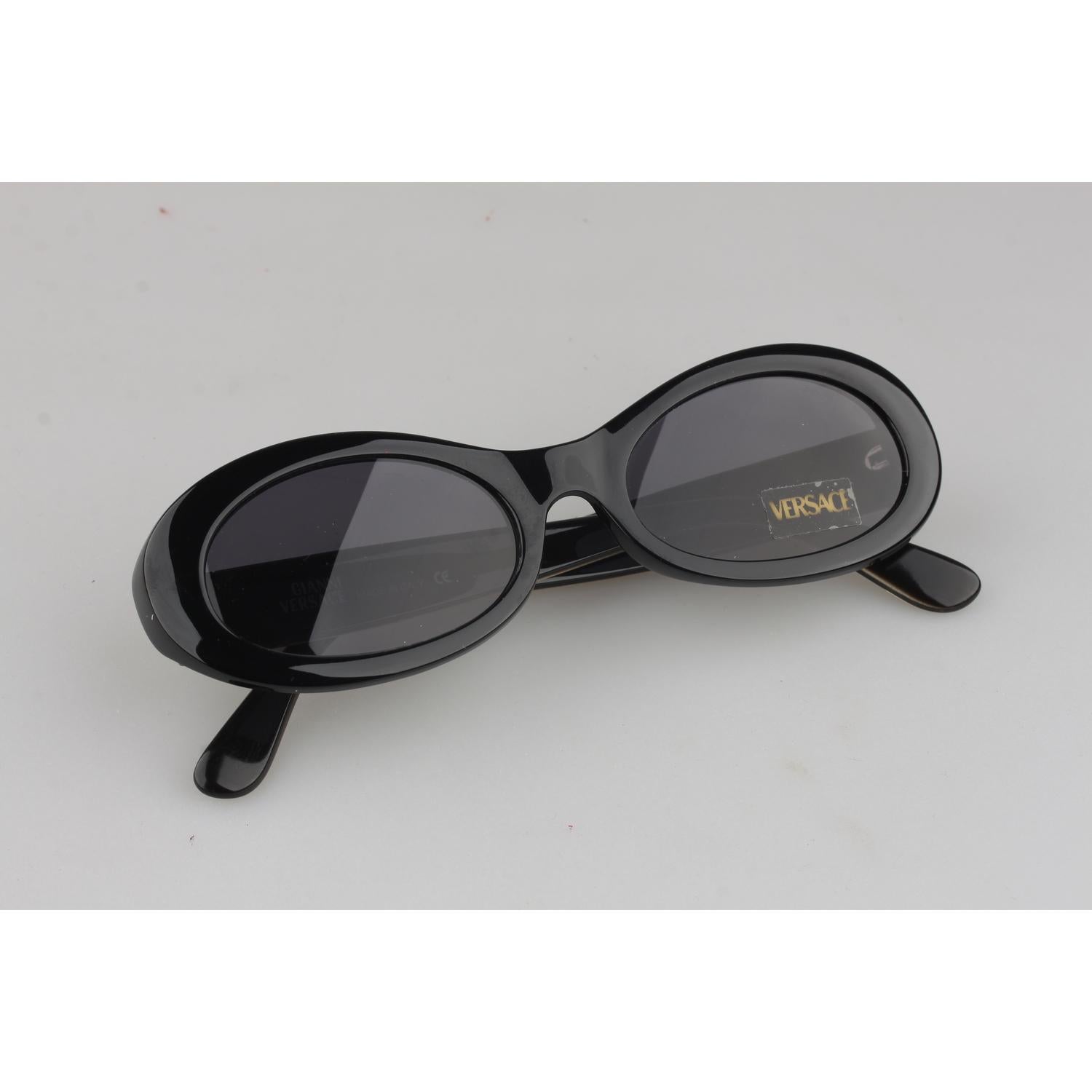 Black, Oval retro shaped vintage sunglasses by Gianni Versace. From the 1980s, Black acetate frame, Versace Medusa silverlogos on the sides. Gianni Versace 100% Total UVA UVB protection original lenses (sticker / label attached). Model refs: Mod.