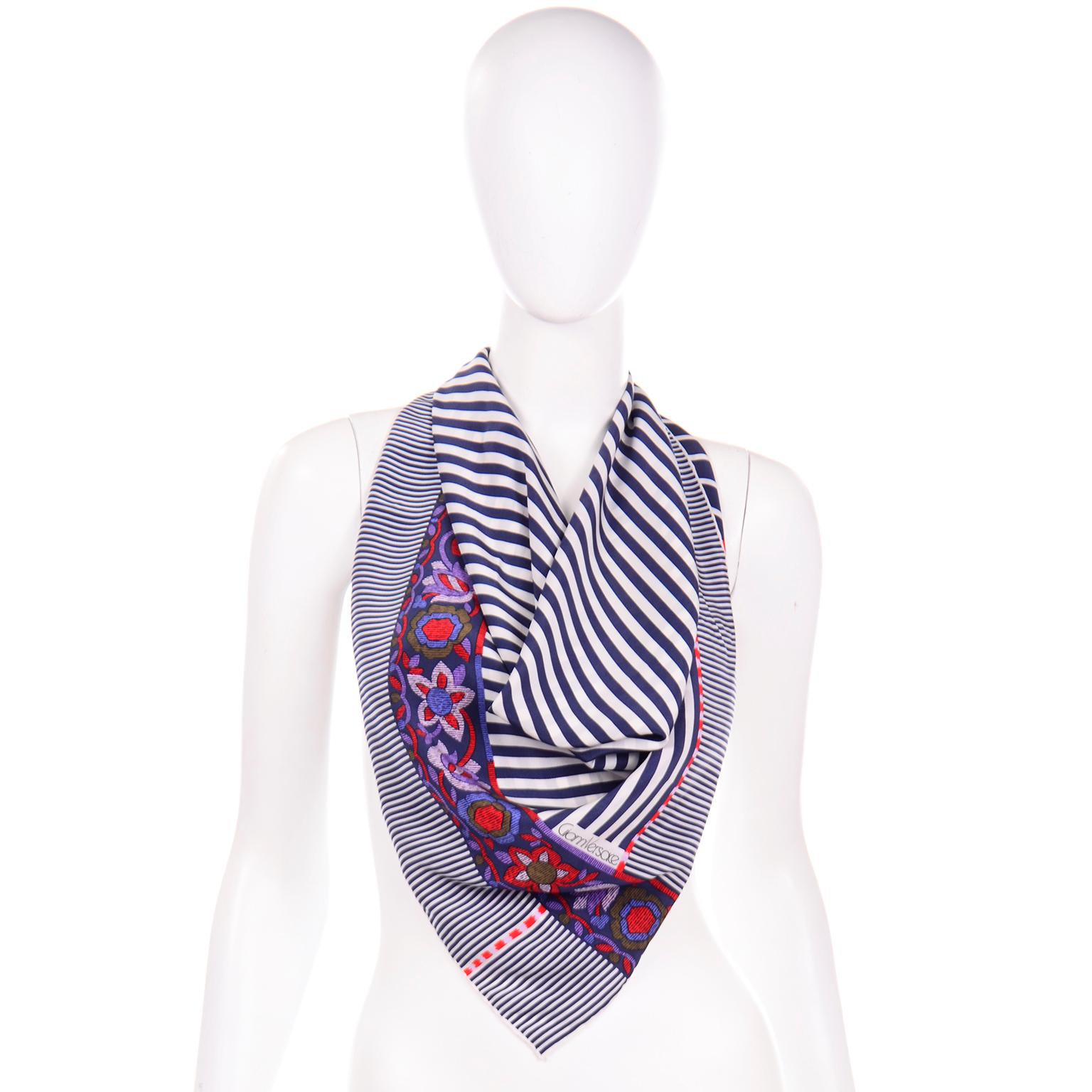 This vintage Gianni Versace scarf is in a navy and white stripe print with colorful chevron stripes and floral print around the trim. The colors in the chevron are in shades of: olive green, red, lavender, purple, blue, and navy. This scarf is hand