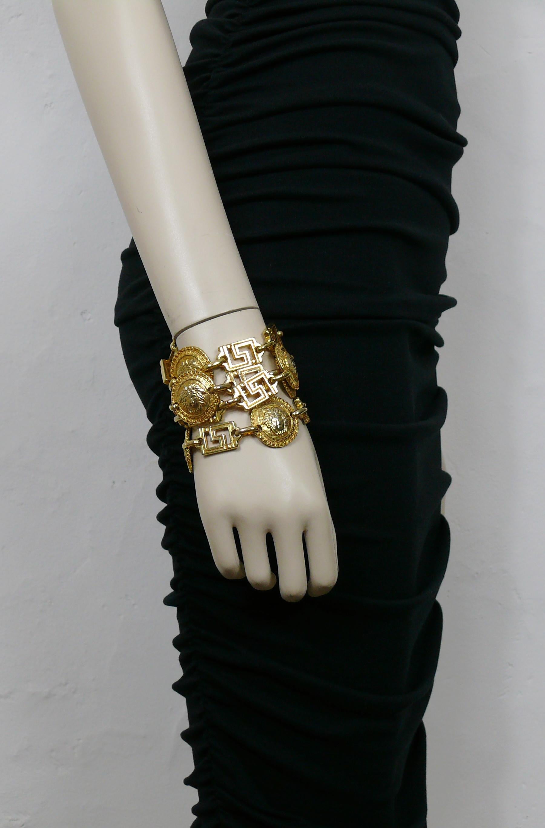 GIANNI VERSACE vintage iconic gold toned four-strand layered cuff bracelet featuring greek key links and round Medusa coins.

Embossed GIANNI VERSACE Made in Italy.

Indicative measurements : length approx. 19.5 cm (7.68 inches) / width approx. 8.2