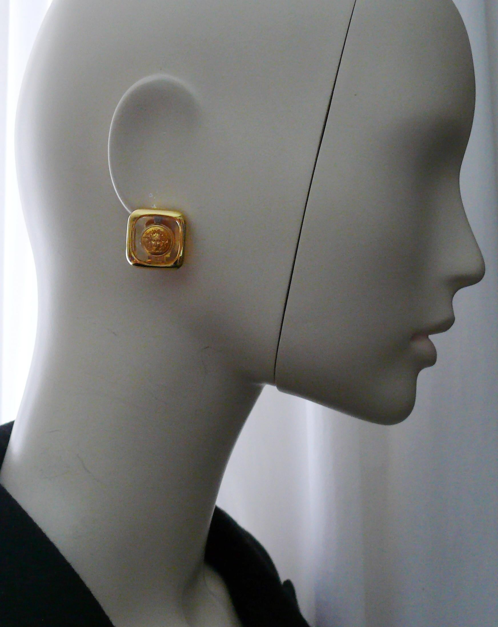 GIANNI VERSACE vintage gold toned clip-on earrings featuring a lucite center with a MEDUSA coin inlaid.

Embossed GIANNI VERSACE Made in Italy.

Indicative measurements : approx. 2.1 cm x 2.2 cm (0.83 inches x 0.87 inches).

Comes with the original
