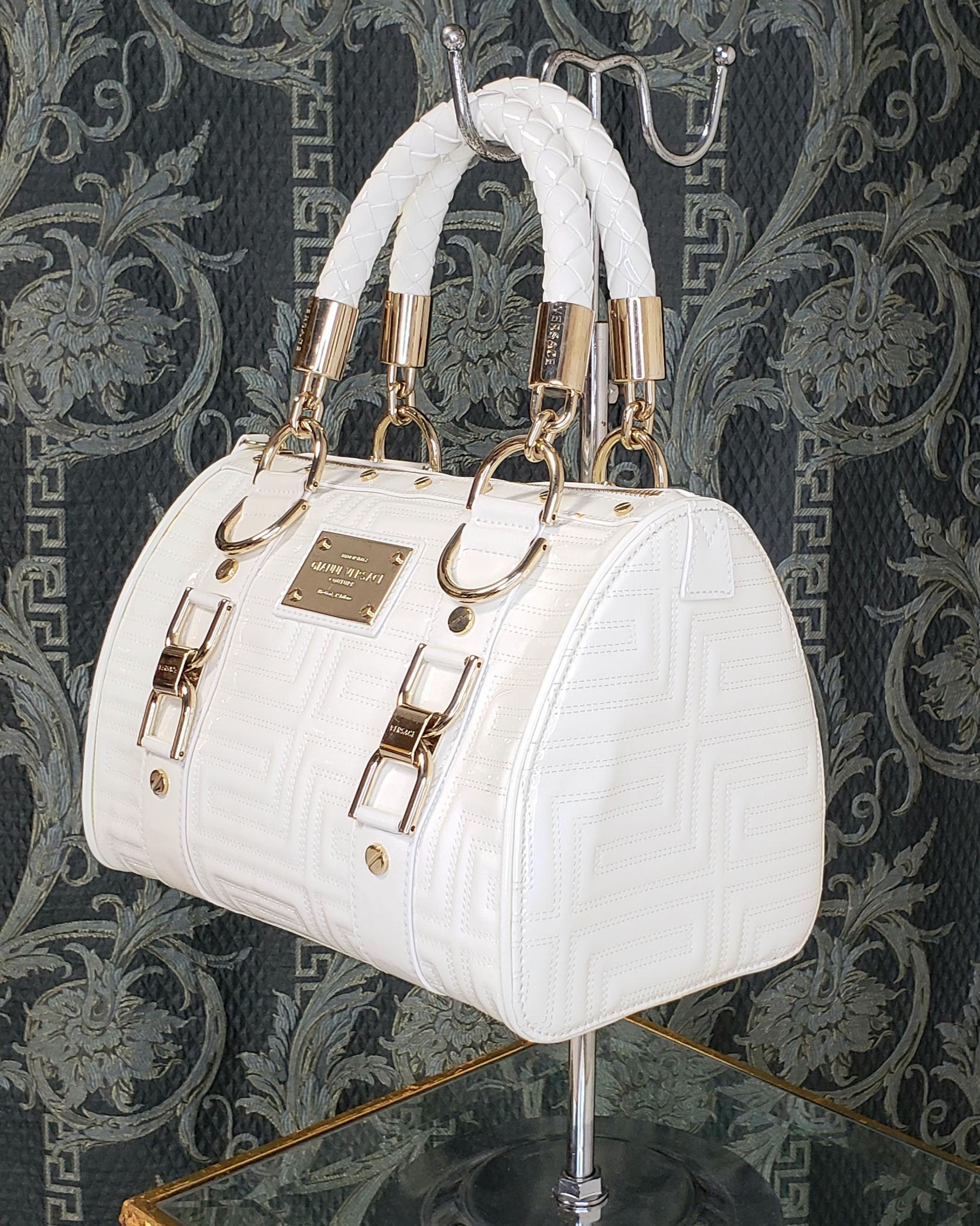 VERSACE 


GIANNI VERSACE COUTURE White Quilted Patent Leather Bag



 Top zip closure



  Five metal feet at base

Satin lining with interior zip and 3 pockets

braided leather top handles with 4'' drop

Enamel gold tone plaque with etched 'Gianni