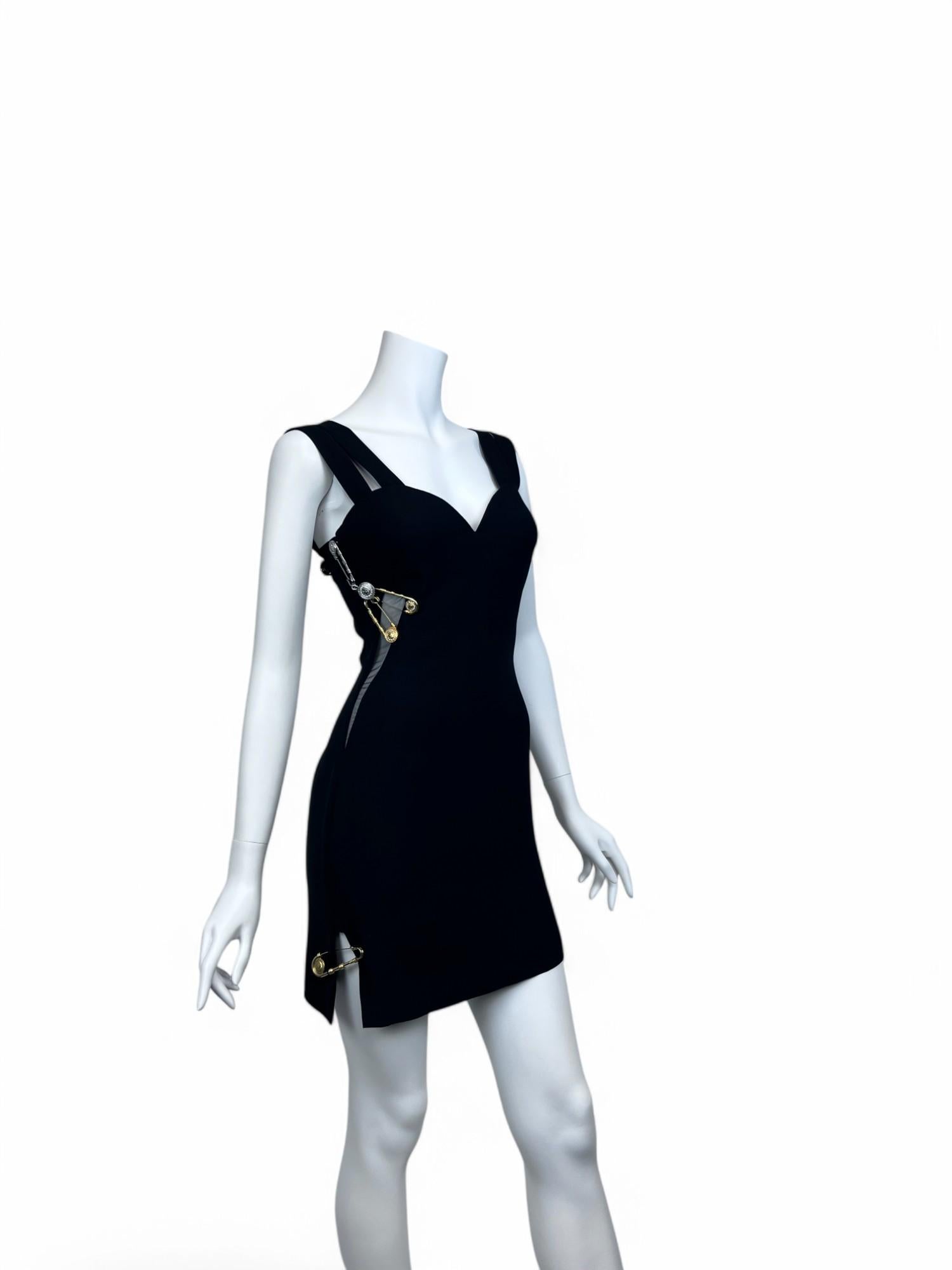 A bold blend of elegance and rebellion, this Gianni Versace Safety Pin Mini Dress is a timeless icon of the house’s daring aesthetic. Crafted from sleek black fabric, the form-fitting silhouette is accented by gold-tone safety pin hardware, adding