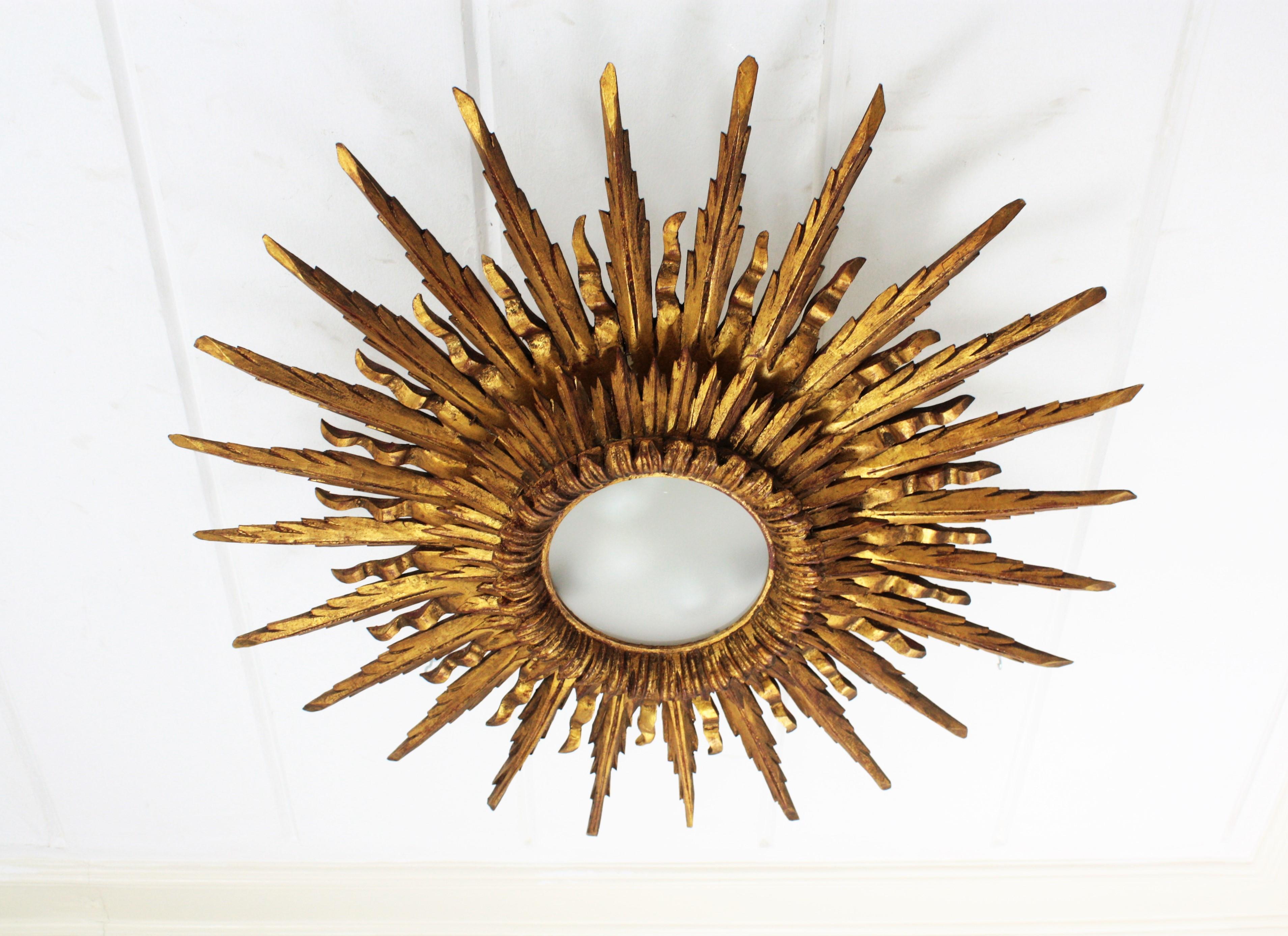 Outstanding giant sized sunburst flush mount or ceiling light fixture in Baroque style made in Spain, 1930s.
Its large size and the two layers of alternating short and large rays, make this piece gorgeous and highly decorative even more face to