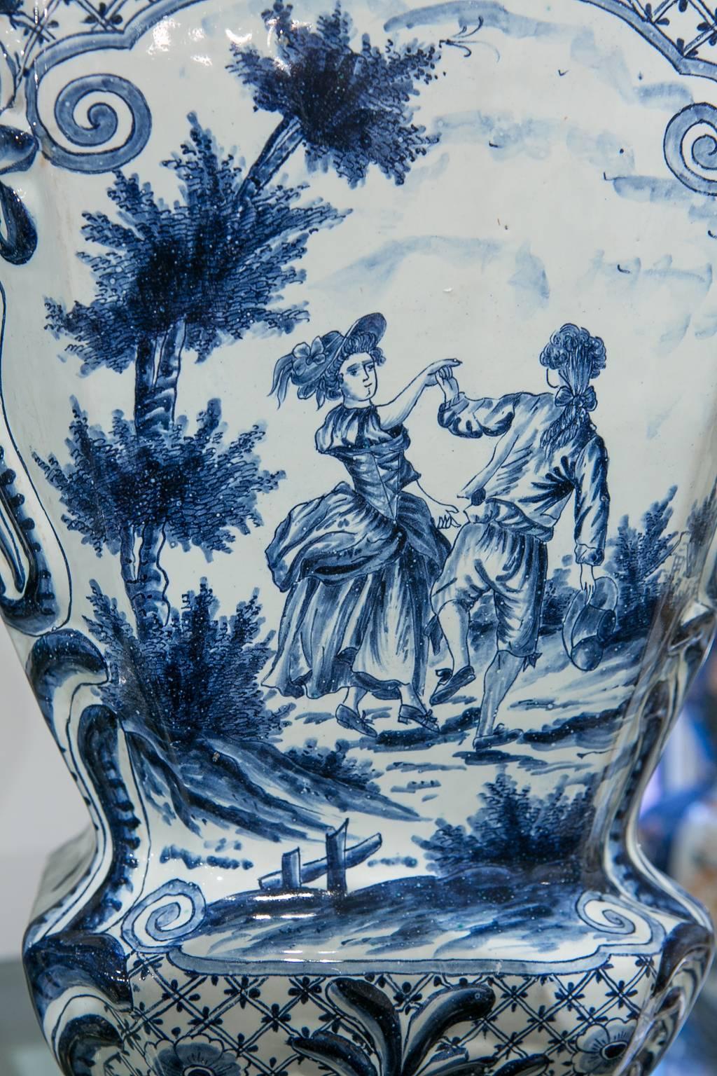 We are pleased to offer this massive blue and white Dutch Delft five-piece garniture with lovely, well painted, romantic scenes showing young couples outdoors. On each vase we see a couple courting or dancing.
One couple is picking apples. They stop