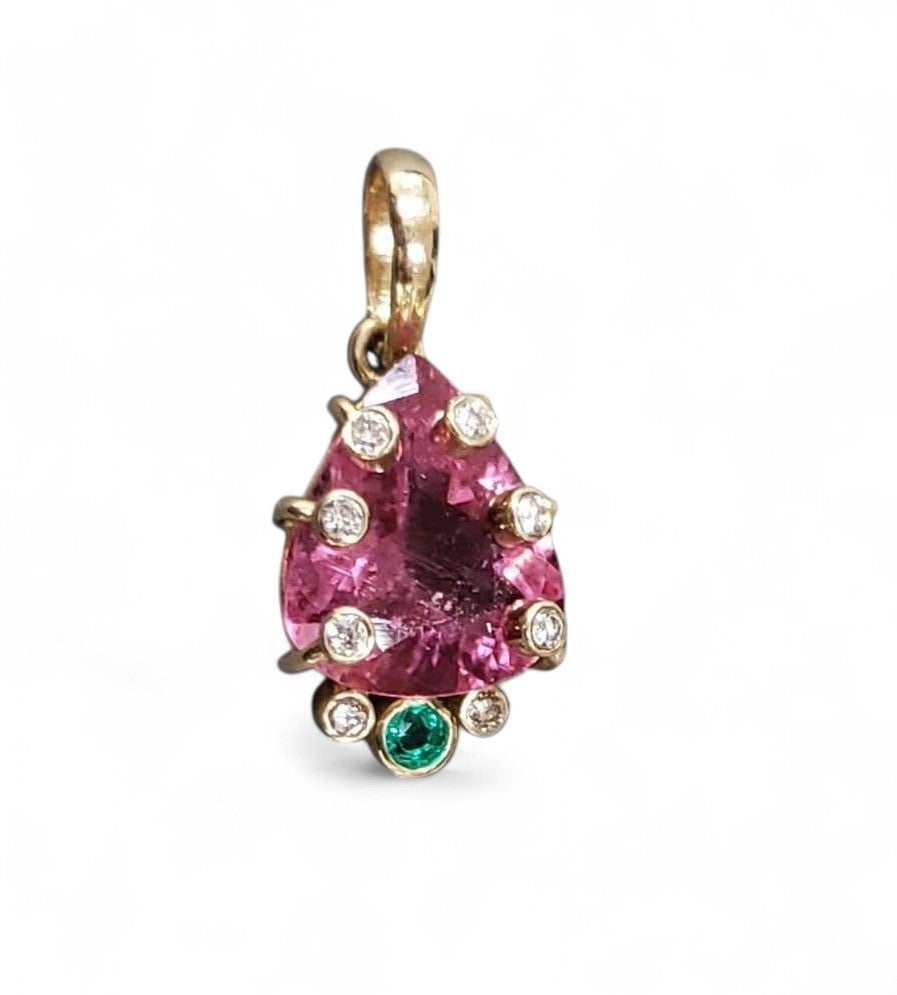 Una gran turmalina rubelita rosa intenso, tallada en facetas y en forma de pera, que atrapa la luz de forma deslumbrante. Rodeada de 8 brillantes diamantes talla rosa y una brillante esmeralda verde de Zambia.

Este colgante único y llamativo es