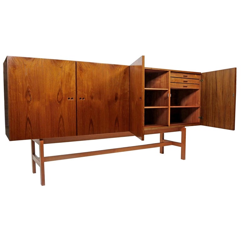 This exceptional credenza was created by Jydsk Mobelindusti of Skanderborg, Denmark. Nearly every section of this massive teak cabinet has unique and organic grain pattern that perfectly harmonizes the sharp architectural lines. Grasp the artfully