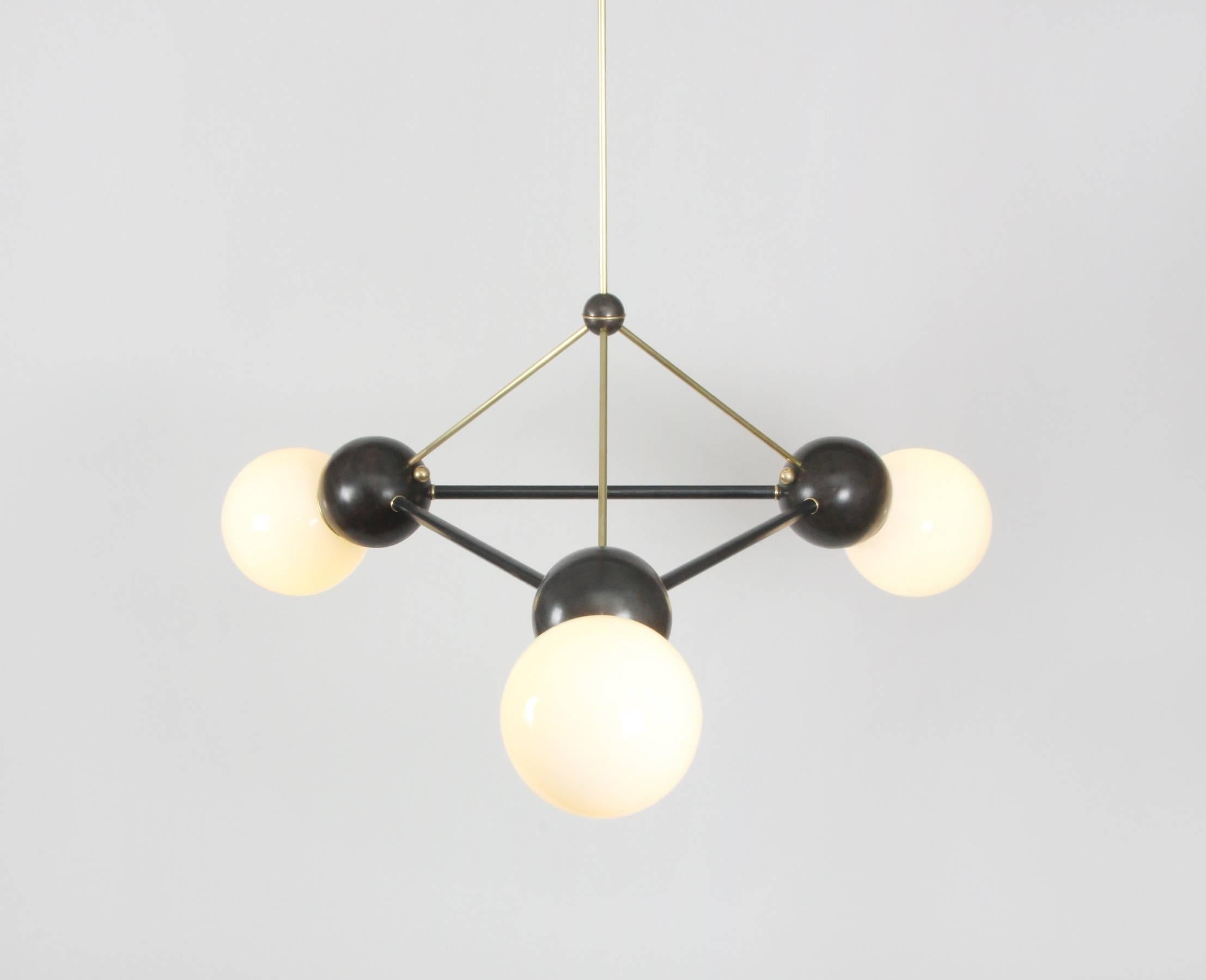 Buoyant, oversized space frame chandelier featuring a combination of brushed brass and oil-rubbed bronze metal finishes with 8-inch milk glass globes and LED illumination. This is a unique item produced in New York by an artist atelier; it was