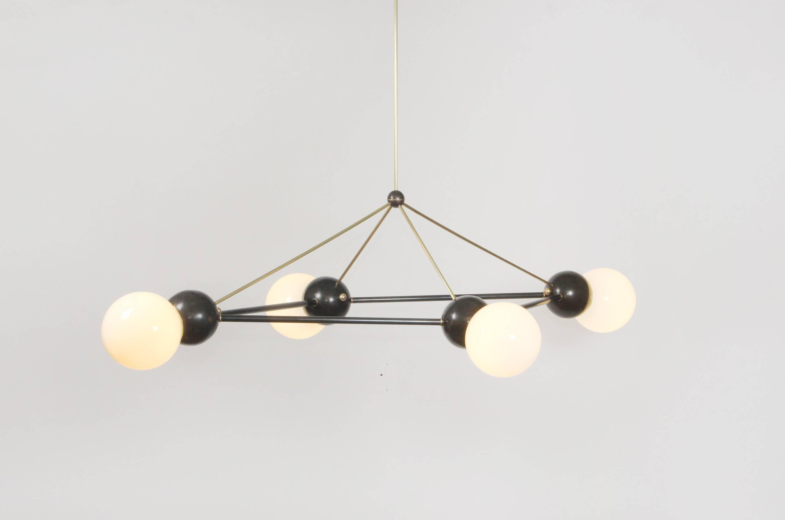 Buoyant, oversized space frame chandelier featuring a combination of brushed brass and oil-rubbed bronze metal finishes with 8-inch milk glass globes and LED illumination. This is a unique item produced in New York by an artist atelier; it was