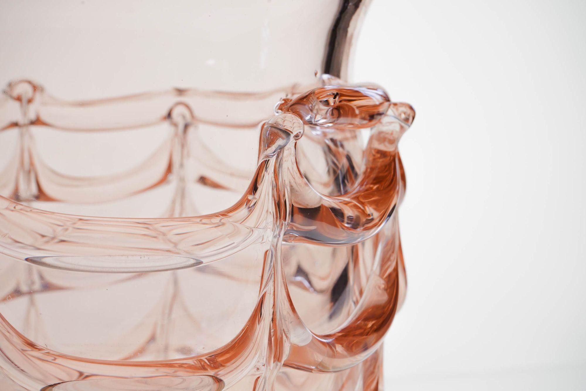 Questo grande vaso presenta una finitura Cordone a Fenicio. Ha una grande perla a spirale che viene tirata in verticale per formare festoni decorativi. Questa tecnica, nota come Fenicio, è stata vista per la prima volta sul vetro fenicio.
Il vaso ha