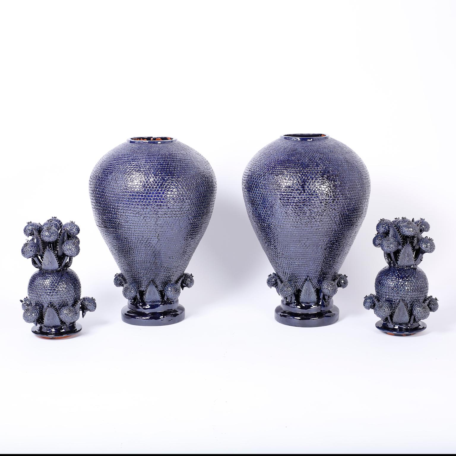 With an extraordinary display of pottery prowess this pair of blue glazed terra cotta urns or jars resembling pineapples take the prize. Featuring dramatic floral lids over a bulbous jar ambitiously decorated in a fish scale motif.