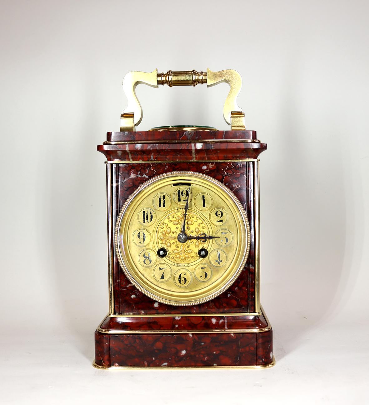 This oversized 'Carriage clock' in an xquisite rouge marble case with gilded mounts and handle, has an eight day movement with english lever platform escapement striking on a bell. The gilded arabic dial has a foliate centre in frosted ormolu with
