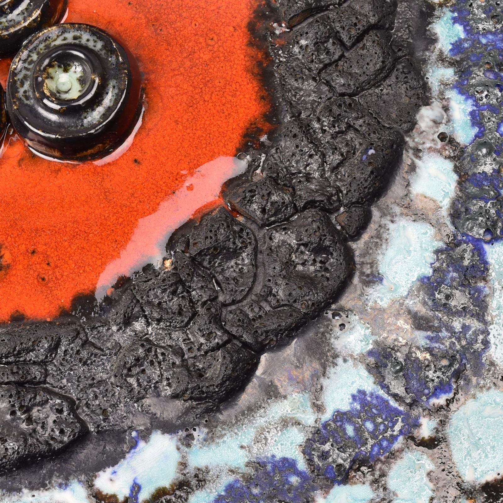This striking, extra-large Ruscha wall disc sculpture showcases the distinctive craftsmanship of mid-century German art pottery. Designed with a vibrant fat lava glaze, this piece displays a visually captivating combination of deep red, intense