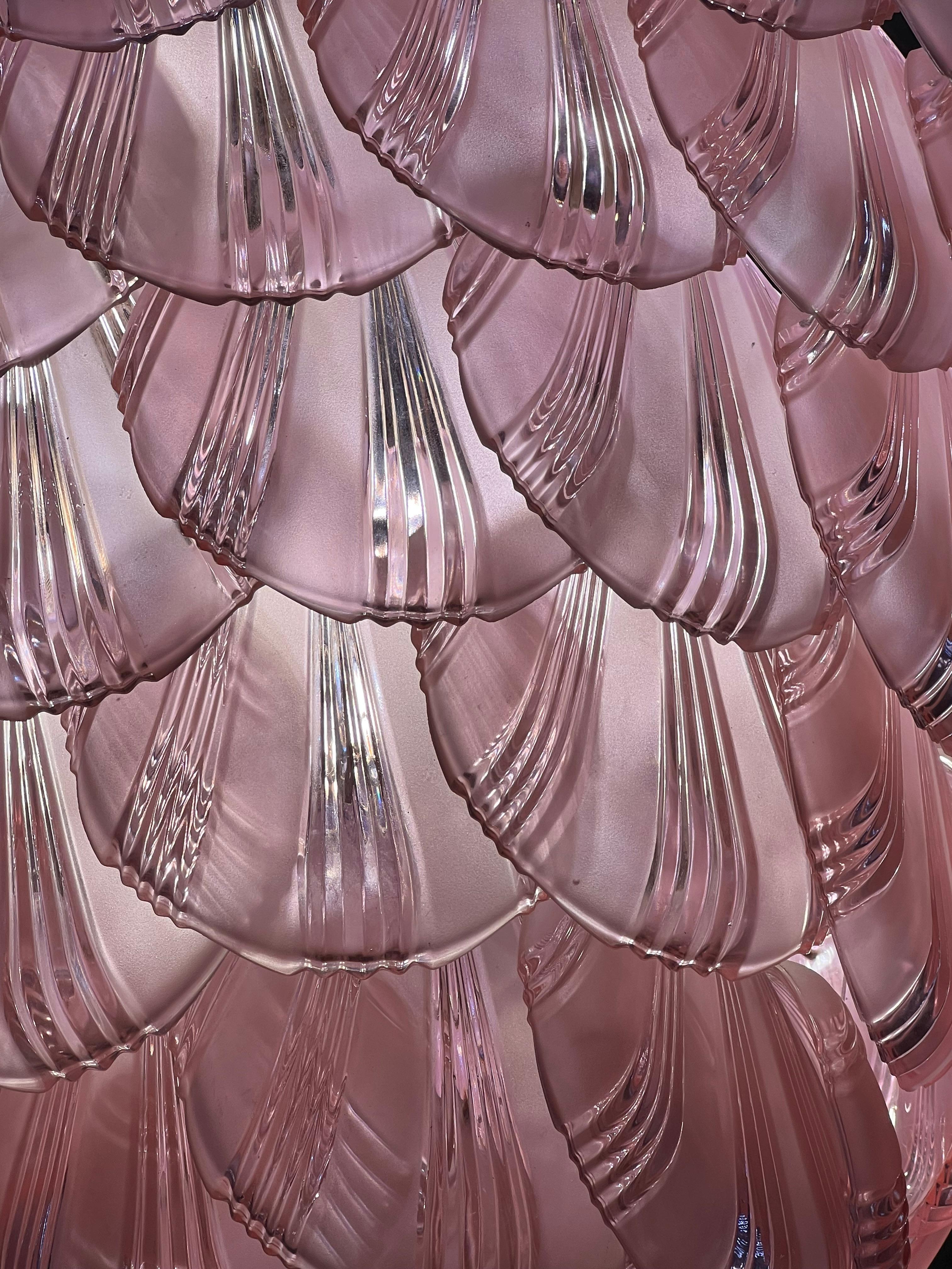 Spettacolare lampadario a forma di grande pigna composto da decine e decine di vetri di Murano a forma di conchiglia. La particolarità di questi occhiali è che cambiano colore non appena vengono illuminati. Da un tenue colore viola diventa un rosa