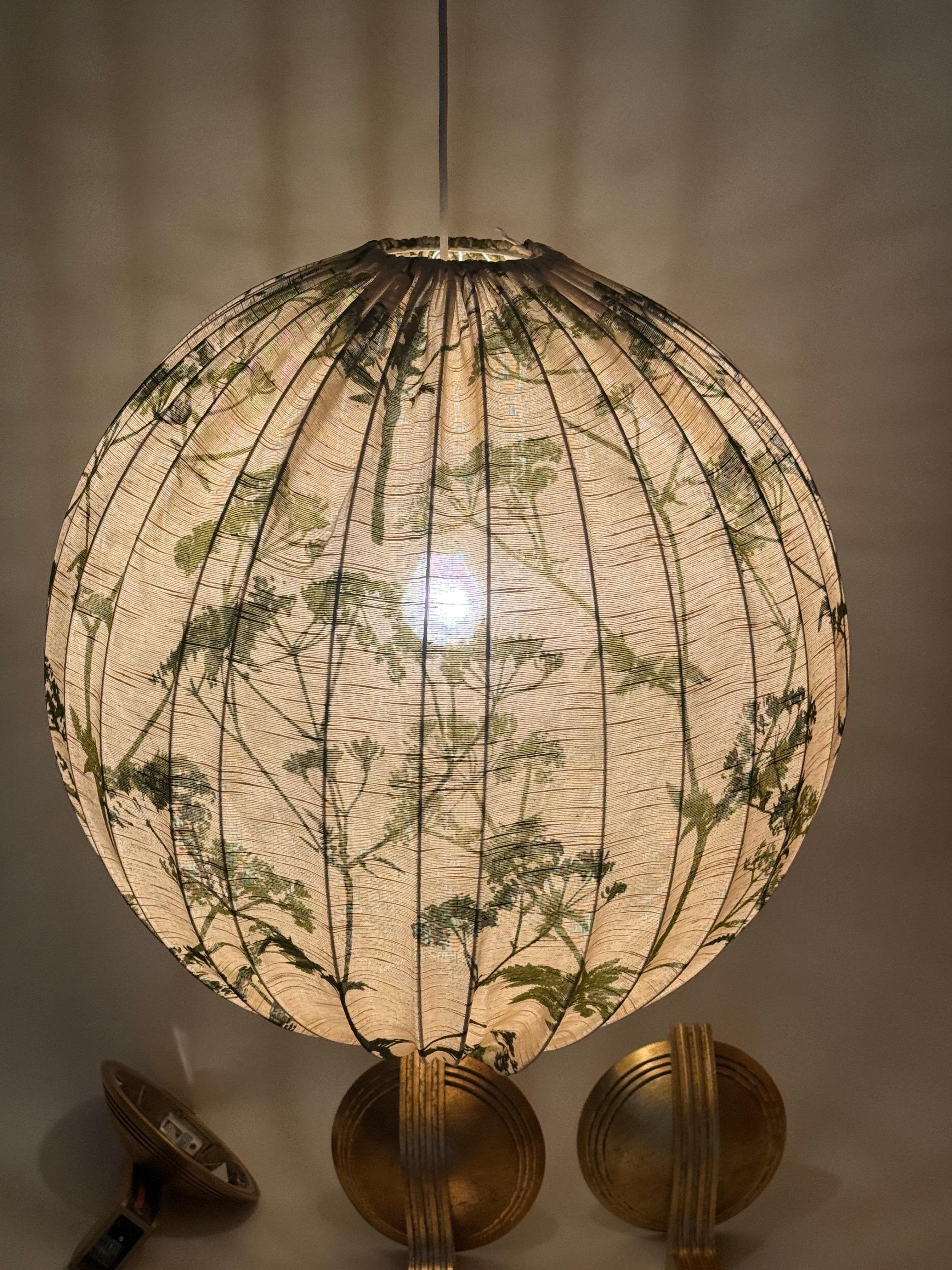 Cette énorme lampe suédoise des années 1960 est extraordinaire par sa taille et sa qualité. Le tissu naturel de haute qualité a été artistiquement imprimé de fleurs dans un vert subtil et chaleureux. La lumière de cette suspension est