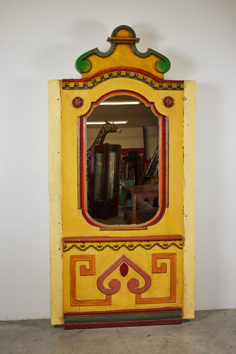 Fantastic statement piece! Gigantic wood carved center mirror from turn of the century carousel. Hand carved wood with layers of original paint surface. Some metal and iron supports around frame. Composite backing to keep mirror in place on reverse.