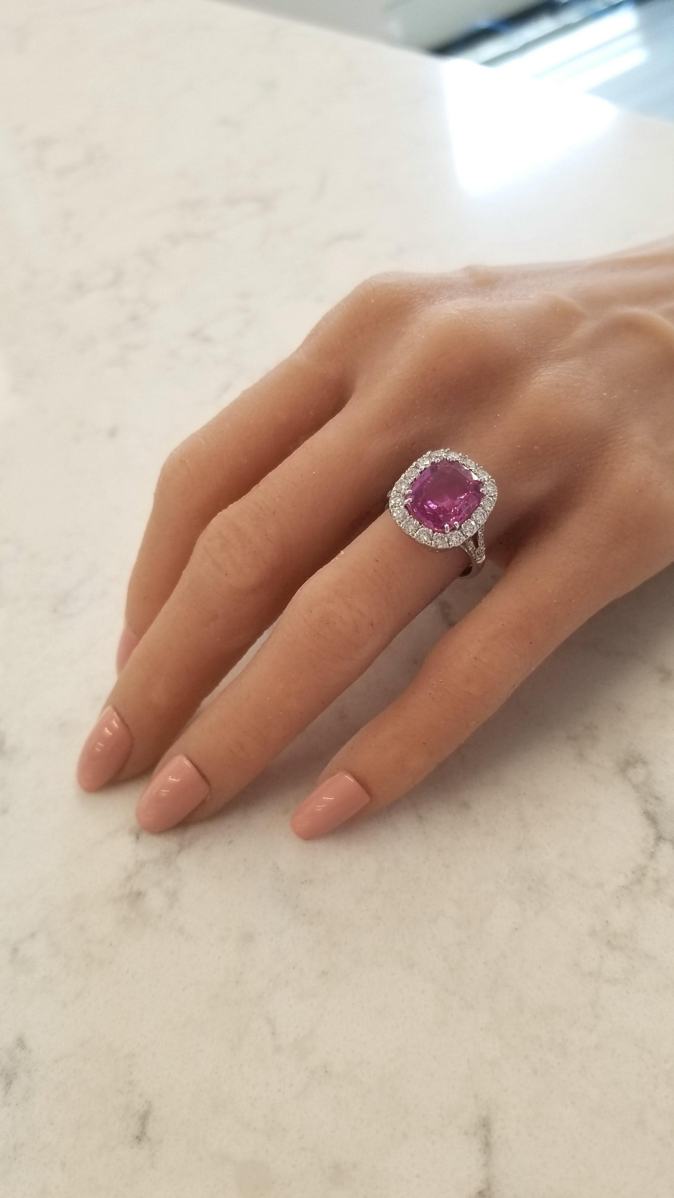 This impressive halo ring features a GIC certified cushion cut pink sapphire that weighs 6.06 carats and measures 11.71-9.82mm. Its color is an intense raspberry purplish-pink. The gem source is Sri Lanka; its transparency and luster are excellent.