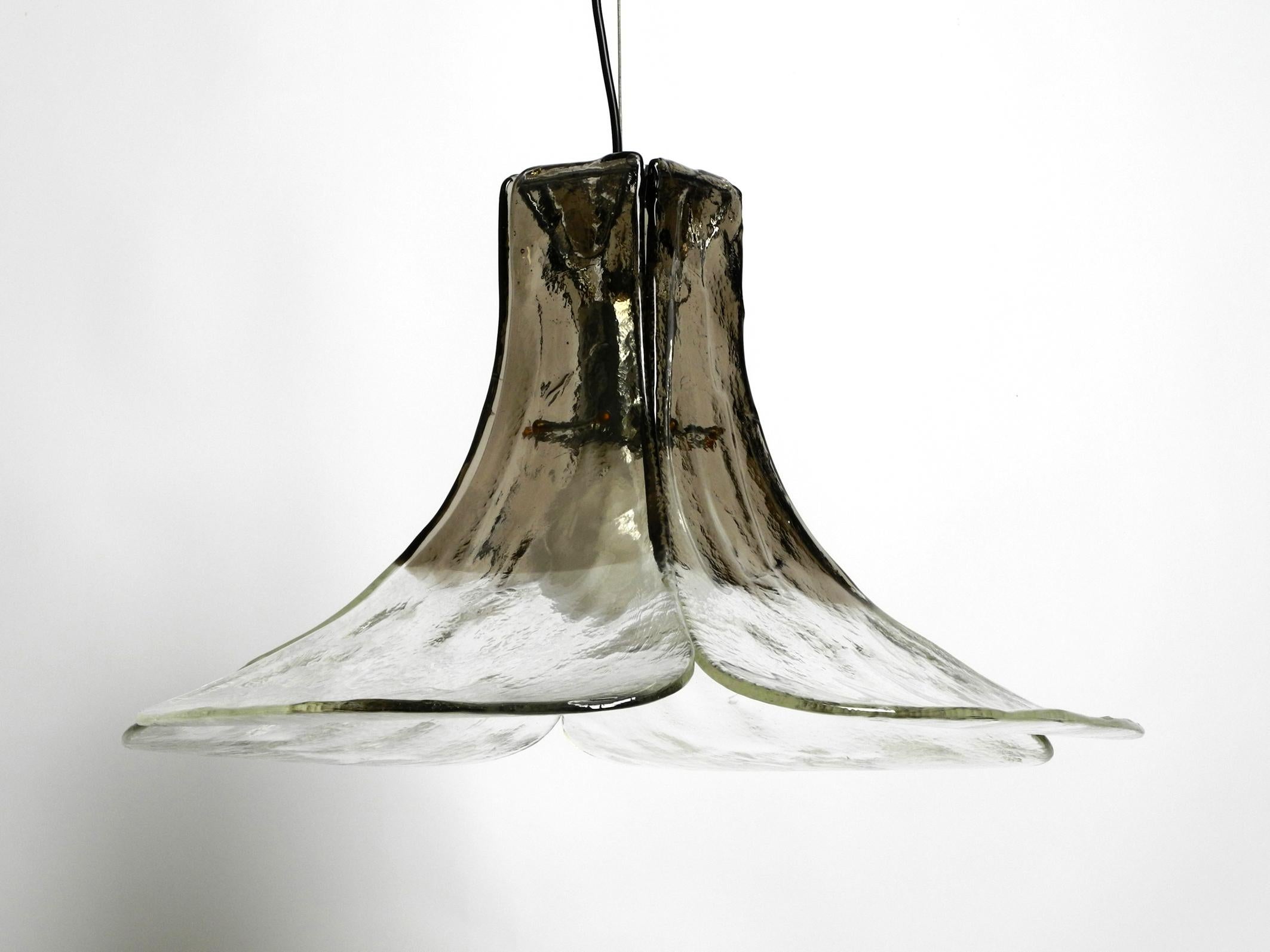 Beautiful original 1960s XXL Mazzega Vetri Murano glass flower ceiling lamp.
Beautiful design with four transparent and brown transparent glass leaves. Each glass is unique.
One E27 socket with steel cable suspension. The length can be