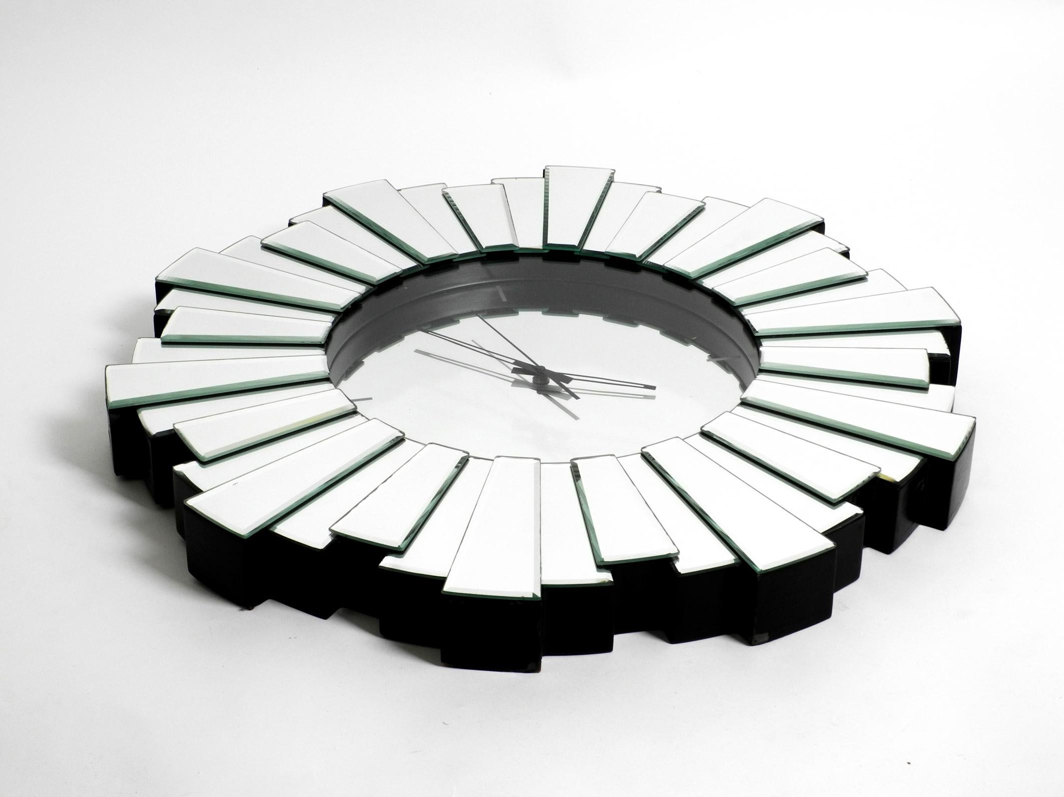 Gigantic very rare heavy Sunburst mirror wall clock from the 1970s. Beautiful elaborate high quality design. The clock has a body made of black lacquered wood, at the front there are 3 mirror elements of different lengths which create a looking like