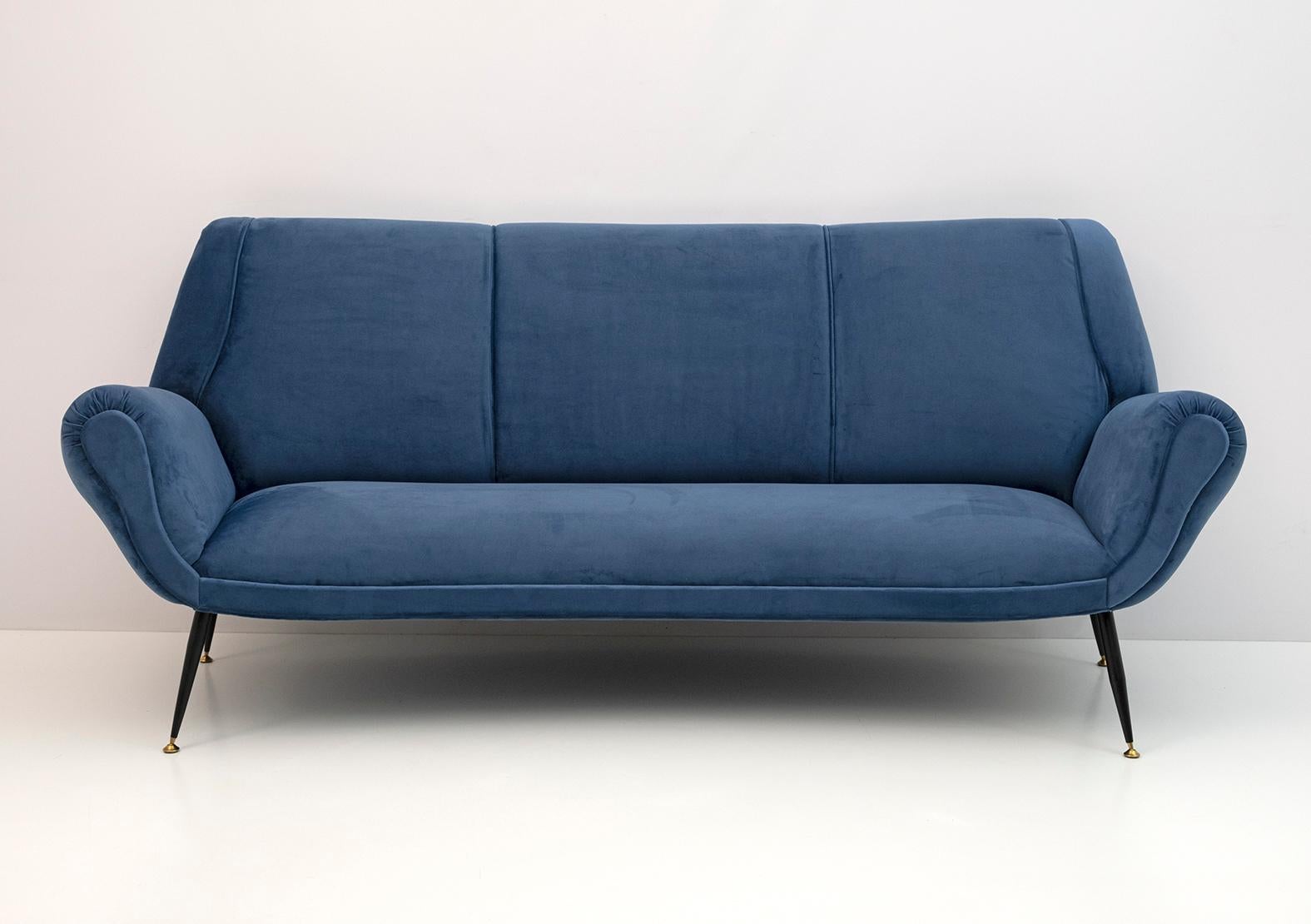 Canapé incurvé conçu par Gigi Radice pour Minotti. Il a été réalisé avec une structure en bois massif et une tapisserie en velours bleu avec des pieds en métal et en laiton. La structure est authentique, seuls le rembourrage et le padding ont été