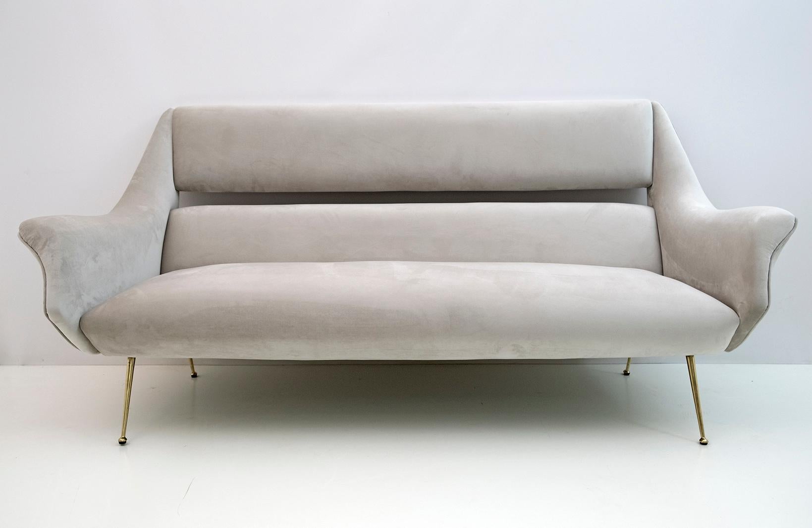 Canapé conçu par Gigi Radice pour Minotti. Réalisé avec une structure en bois massif, un revêtement en velours gris clair et des pieds en laiton poli. Le canapé est authentique, seule la tapisserie a été remplacée.