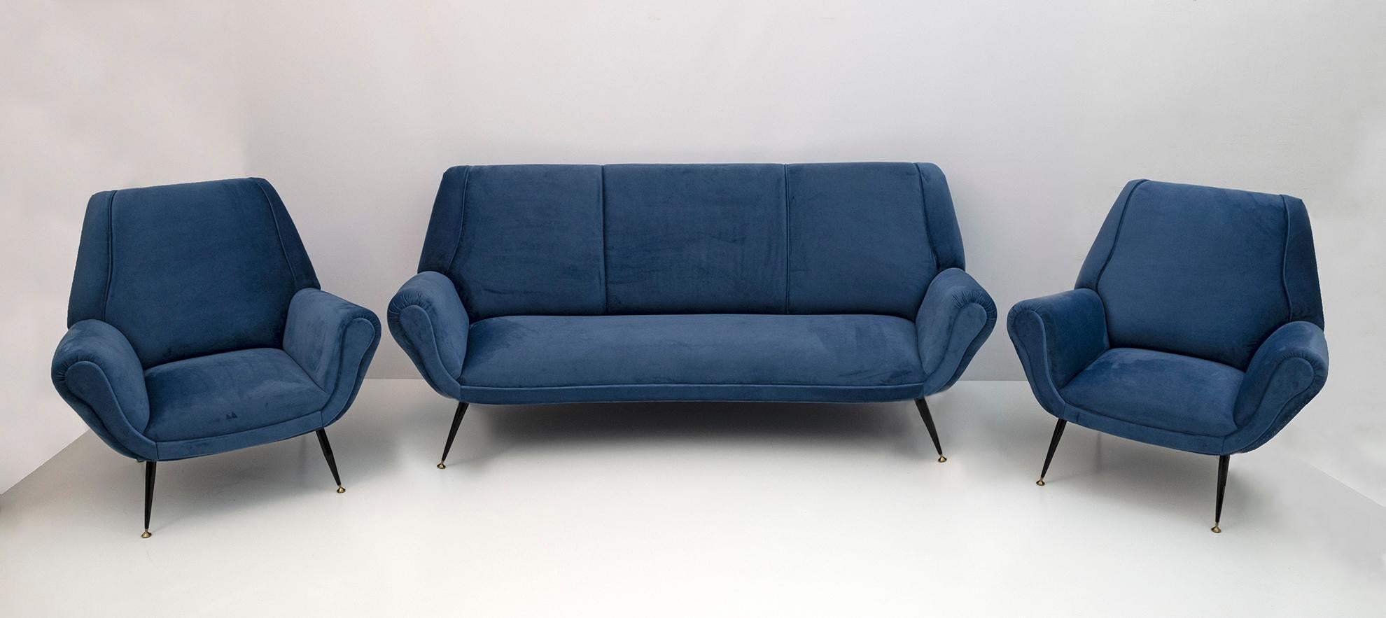 Pair of armchairs and curved sofa designed by Gigi Radice for Minotti. They are made with solid wood structure and blue velvet upholstery with metal and brass legs. The structures are authentic, only the upholstery and padding have been
