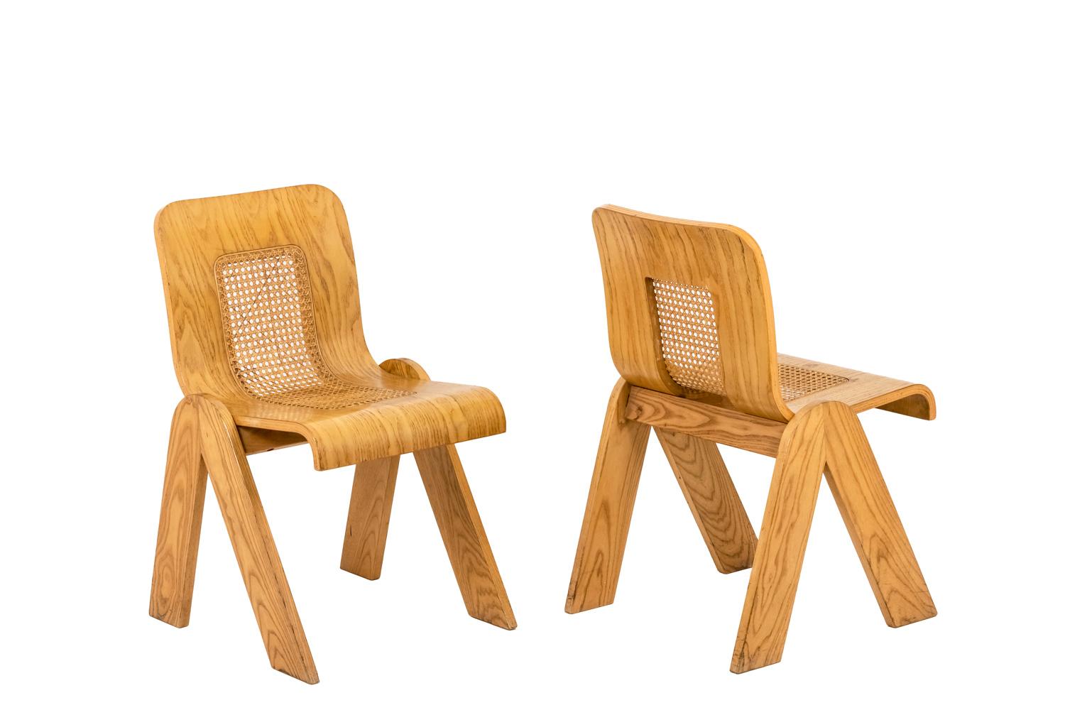 Set of four chairs in curved plywood and beech veneer lined with cane. Curved structure forming the seat and the back. Caned central part. Chair standing on four legs joining under the seat to form an inverted V.

Work realized in the 1970s.

 